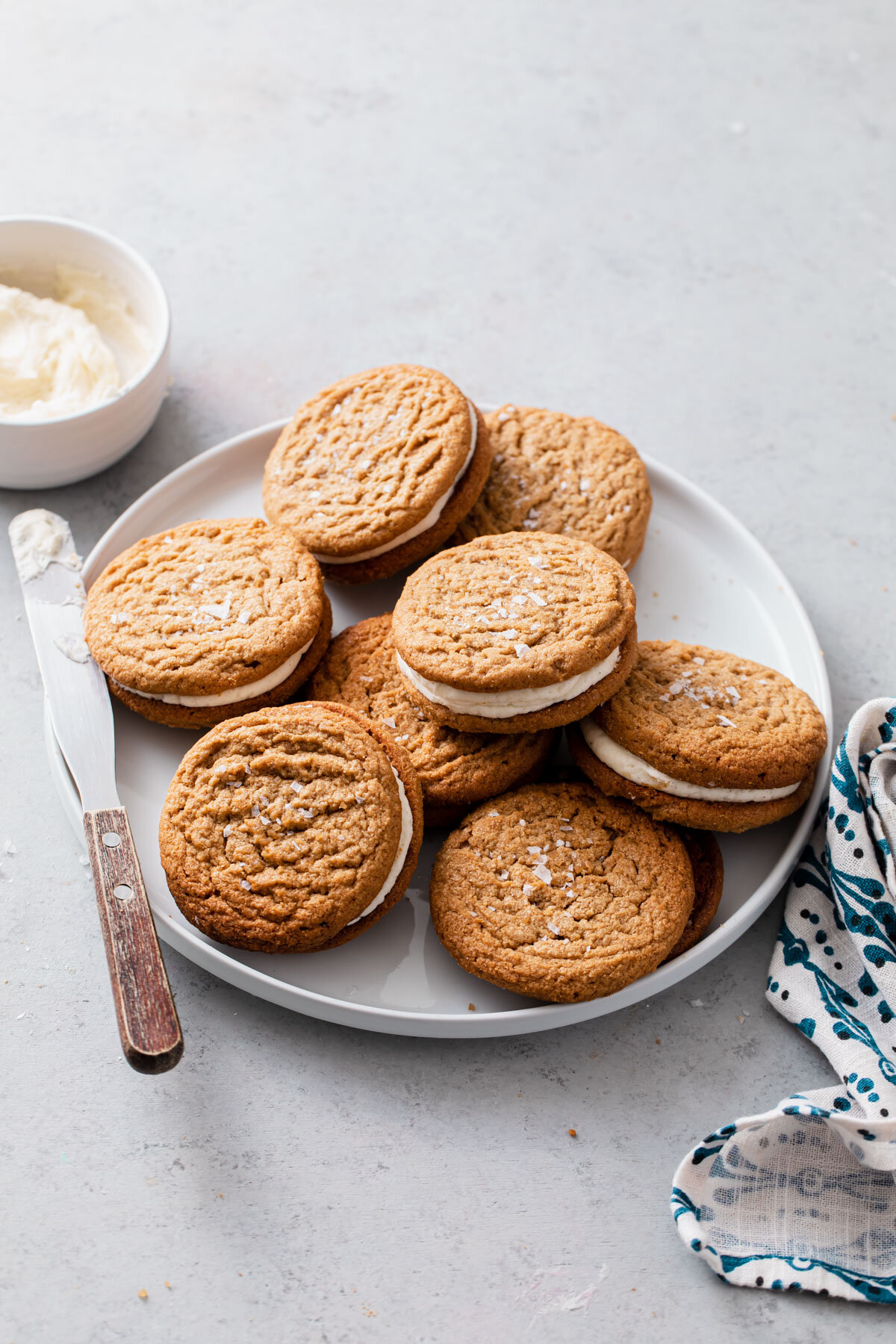 A plate of Flourless Peanut Butter Cookies filled with vanilla frosting.