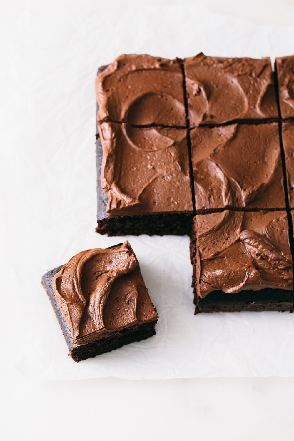 A sliced chocolate sheet cake with swirls of fluffy whipped chocolate ganache frosting.