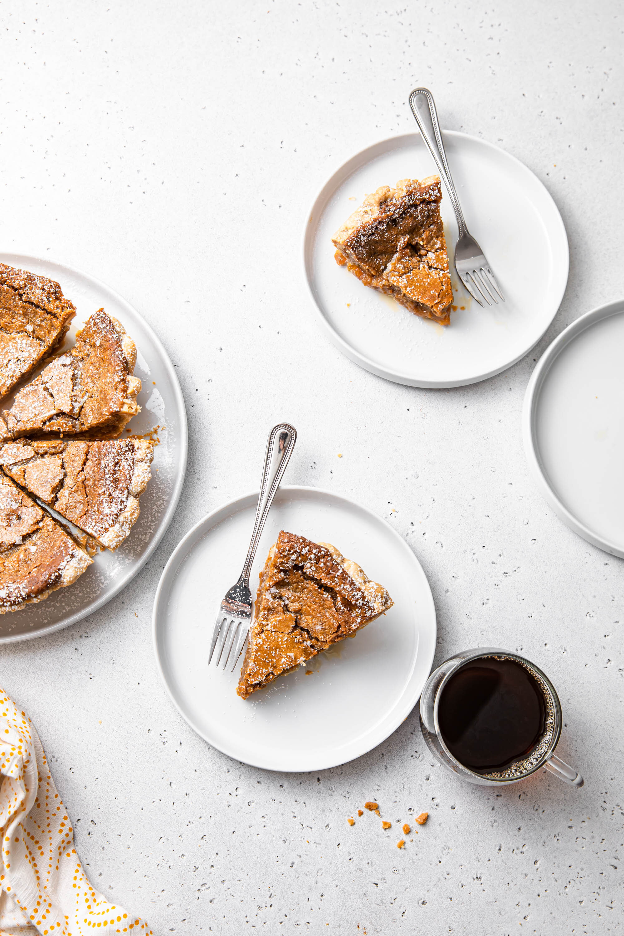 Slices of French Canadian Maple Sugar Pie with powdered sugar on top and a side of coffee.