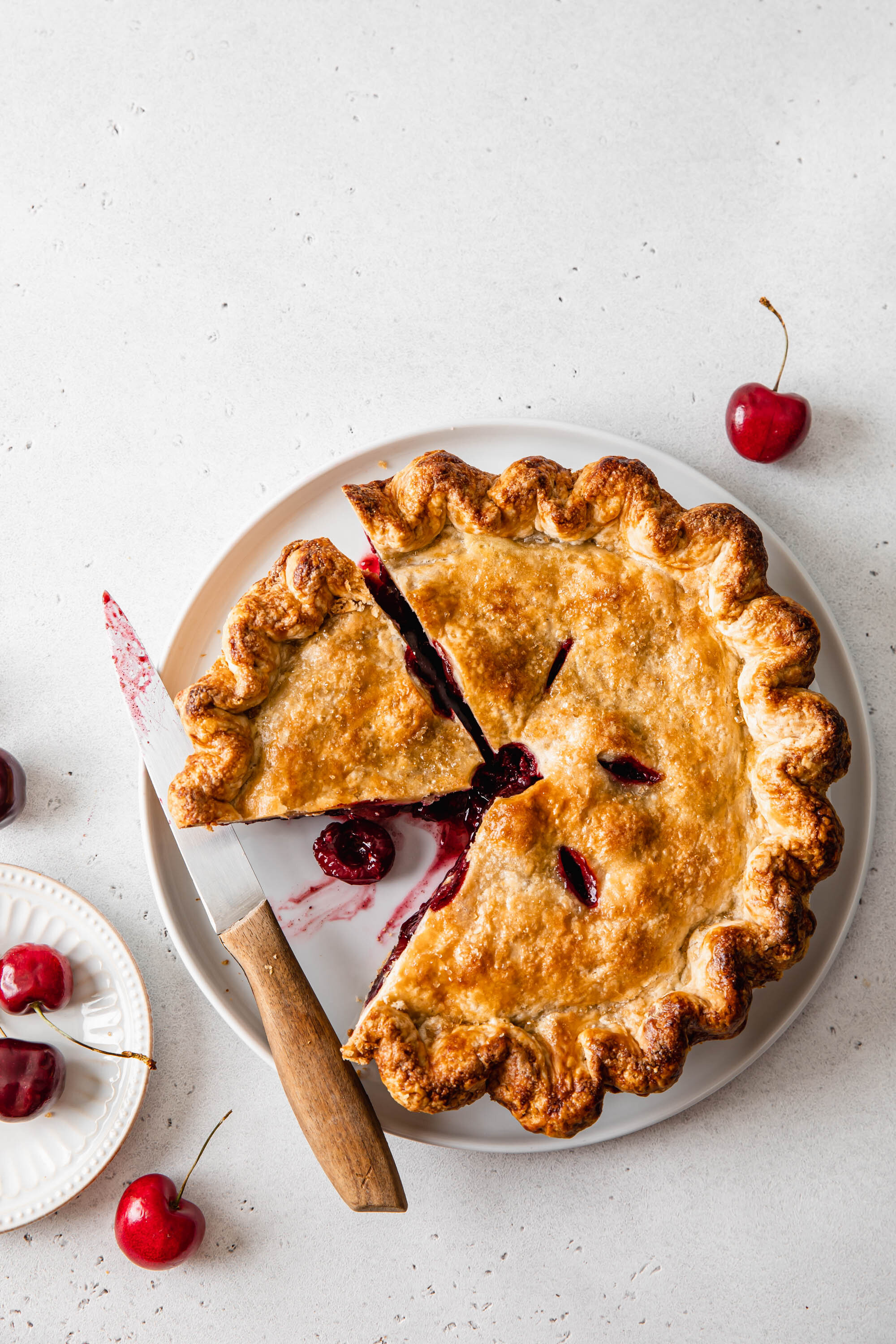 A sliced sweet cherry pie with a golden, flaky pie crust.