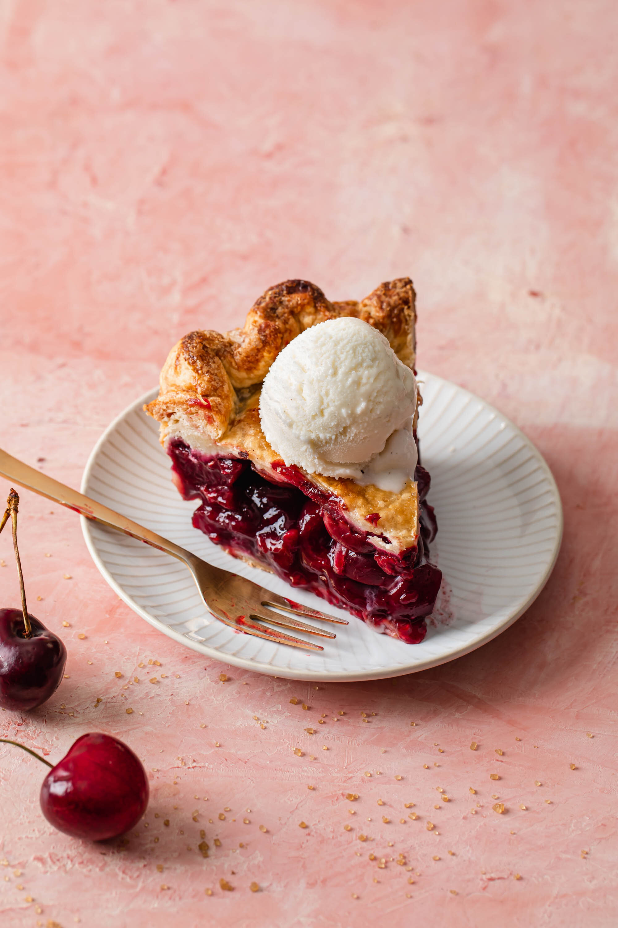 A slice of fresh cherry pie with vanilla ice cream on top.