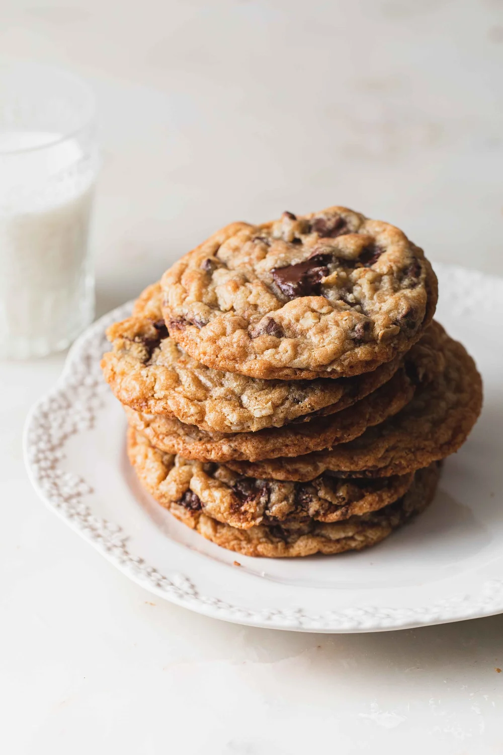 A stack of oatmeal Nutella stuffed cookies on a clean white plate set on a marble tabletop.