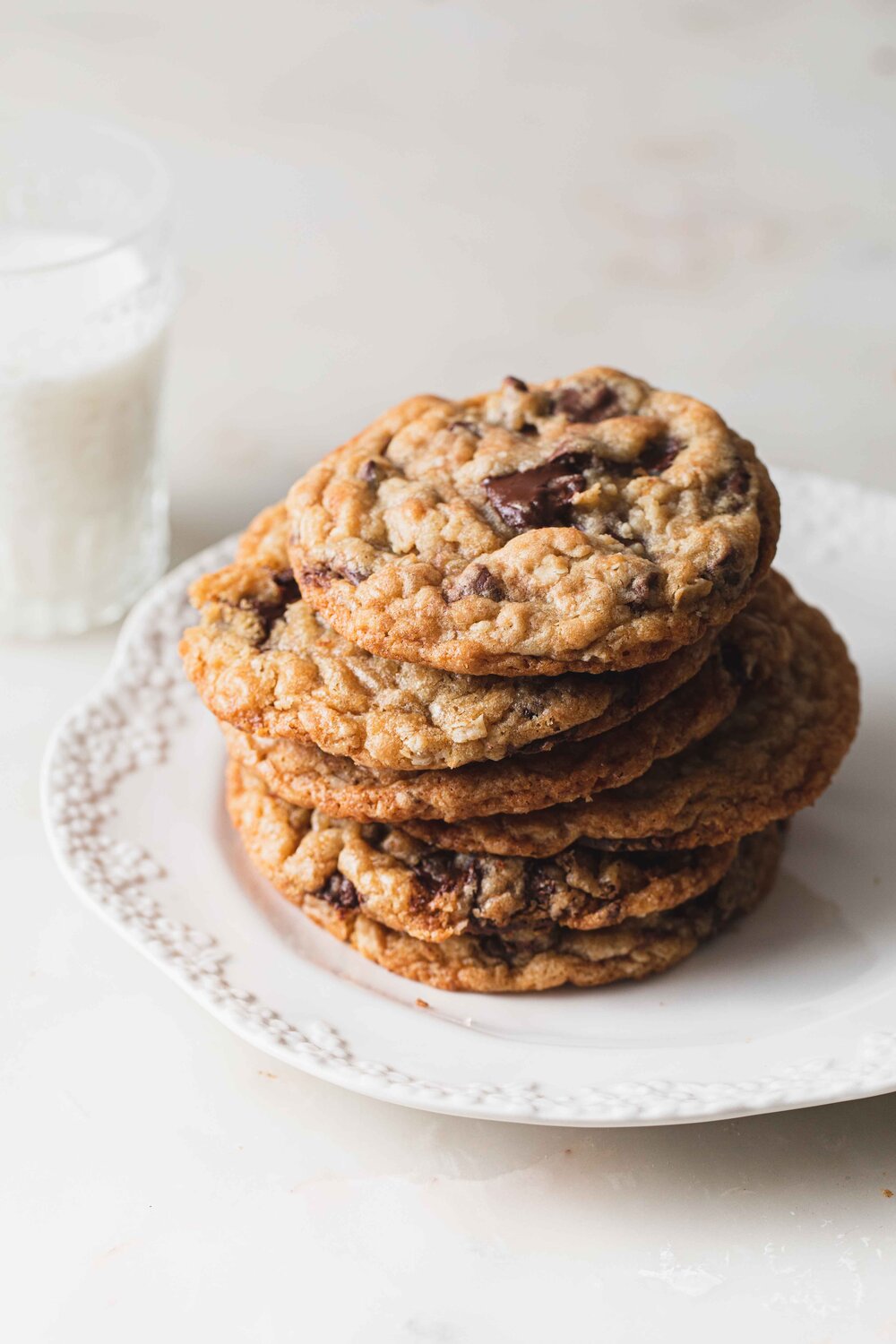 A stack of oatmeal Nutella stuffed cookies on a clean white plate set on a marble tabletop.
