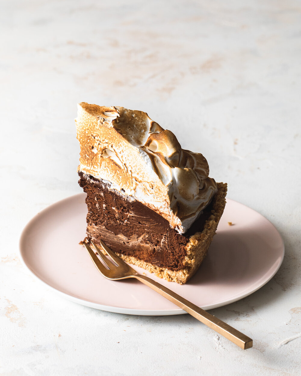 A slice of peanut butter s’mores pie with chocolate peanut butter mousse filling and toasted meringue on top.