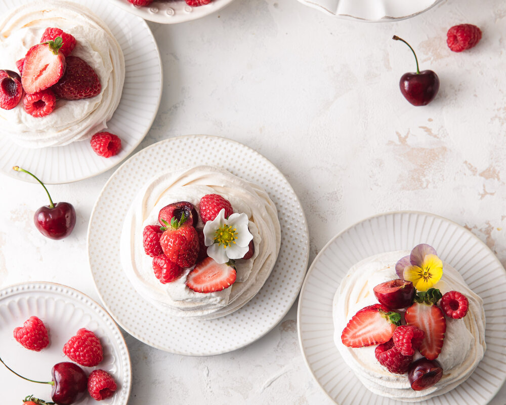 Mini pavlovas using French meringue topped with fresh berries and whipped cream.