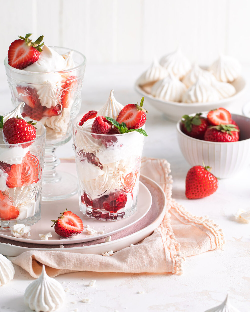 Layered Eton mess with French meringue kisses, berries, and cream.
