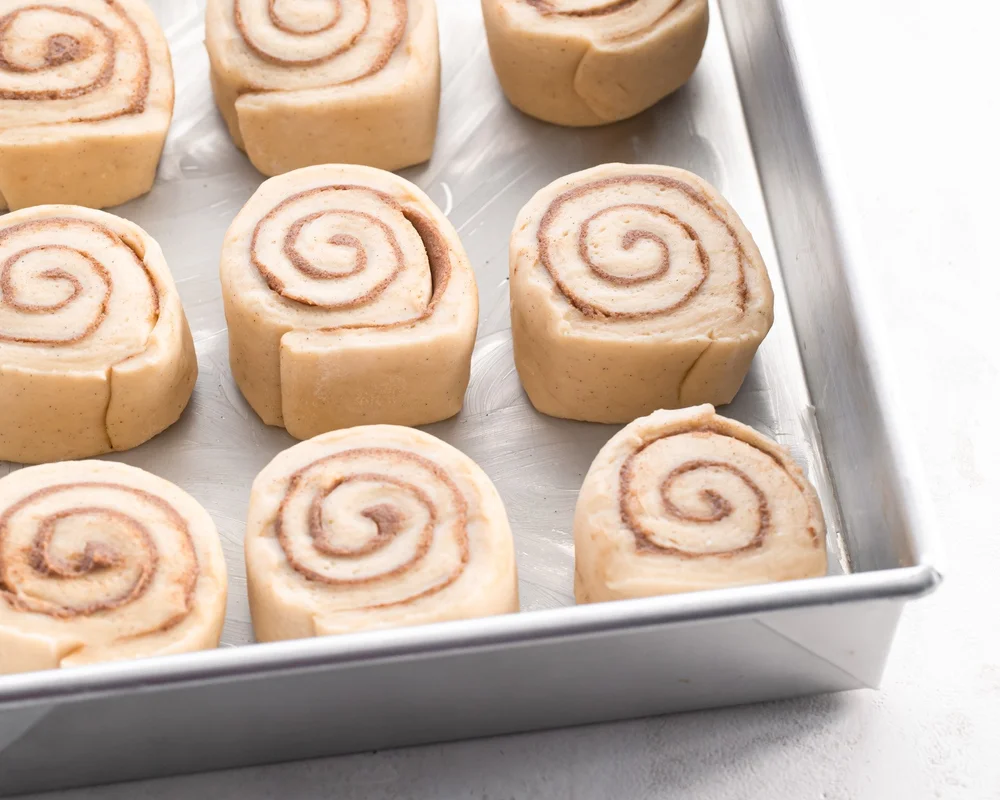 Sliced cinnamon rolls in a baking pan before baking