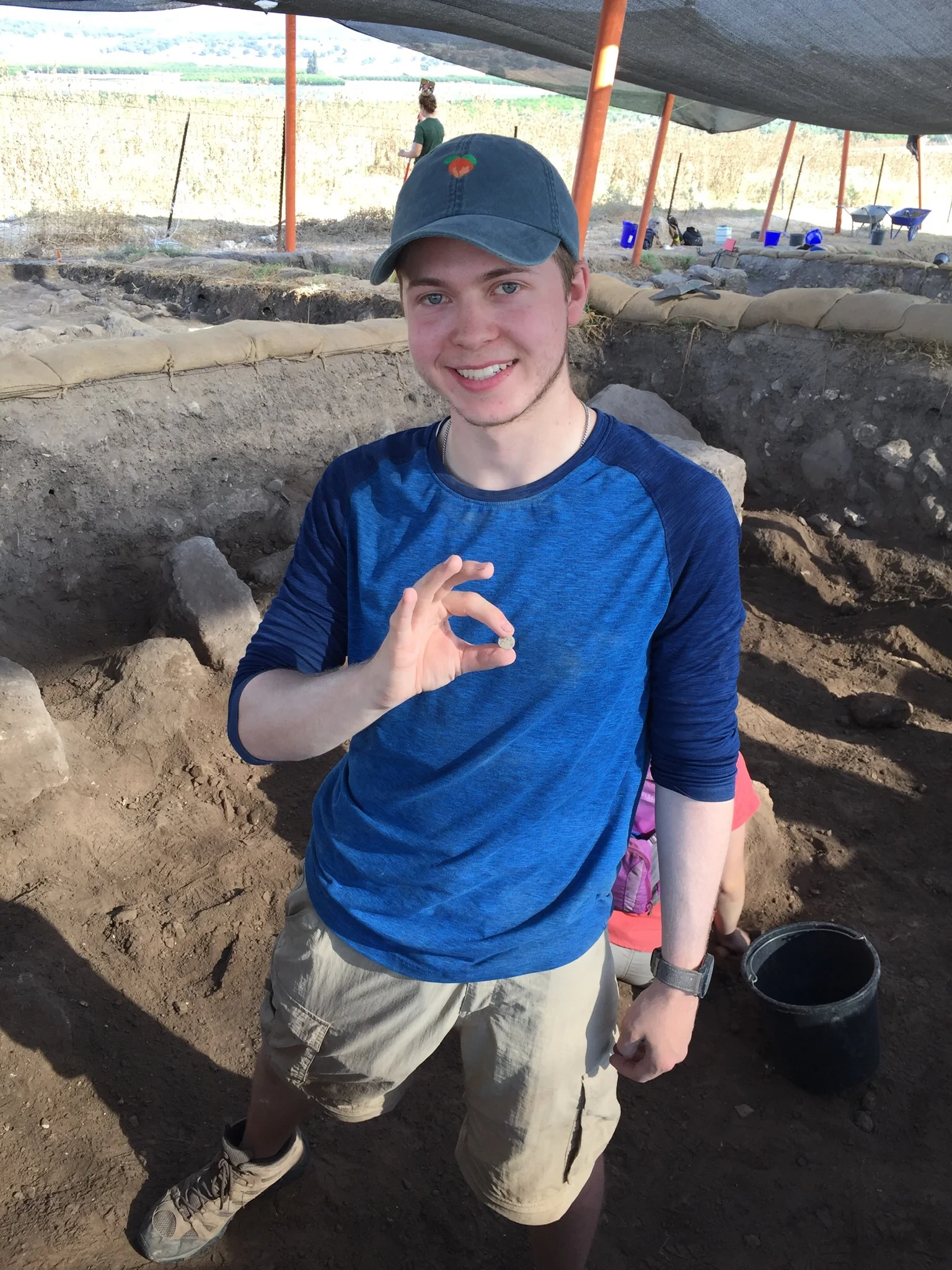 Grid 23/24 volunteer Ethan Preston with a coin he found during excavation