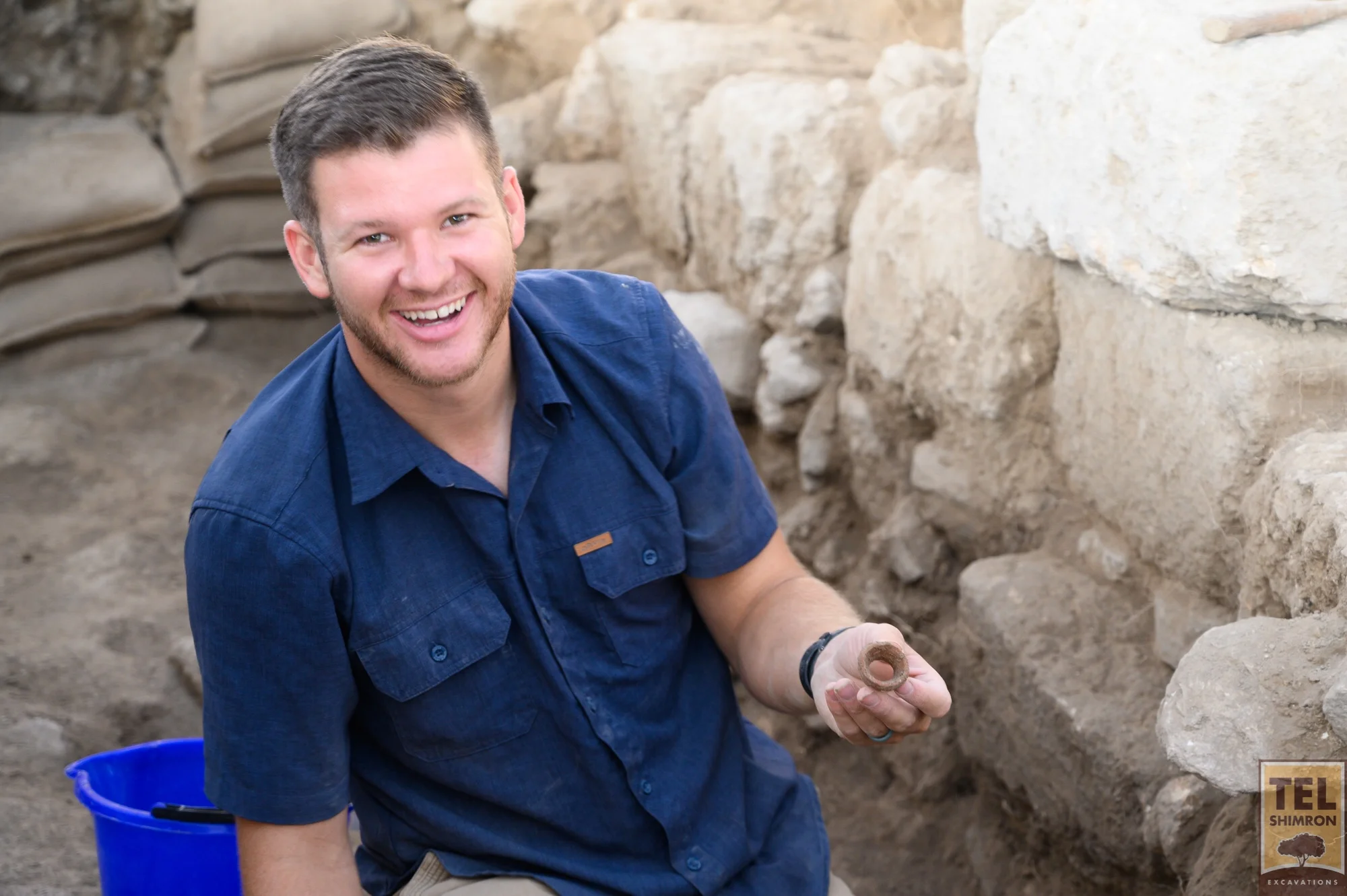 A Grid 23/24 volunteer holds a piece of pottery found during excavation