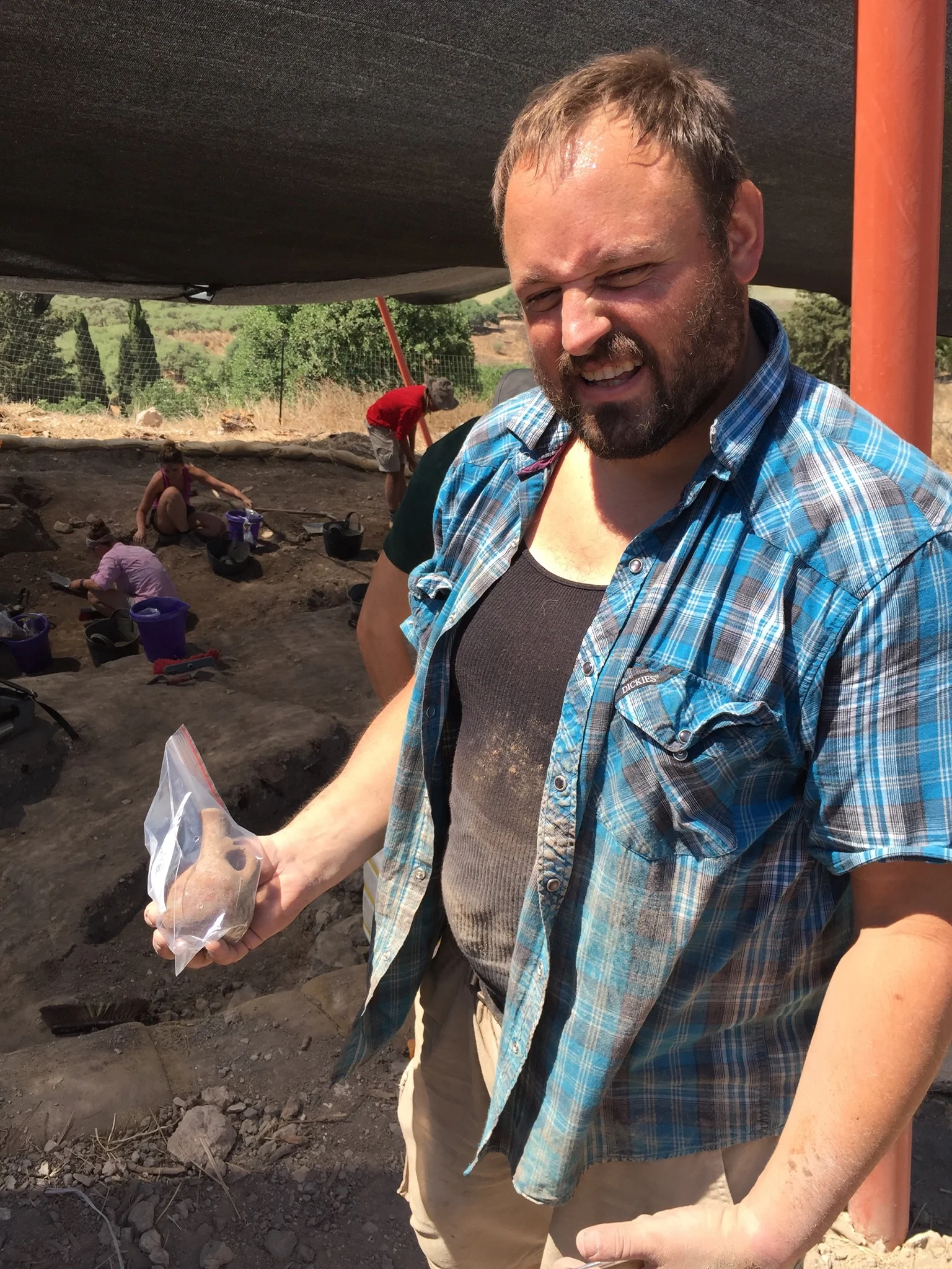Grid Supervisor Josh Walton holding a small juglet found in Grid 33