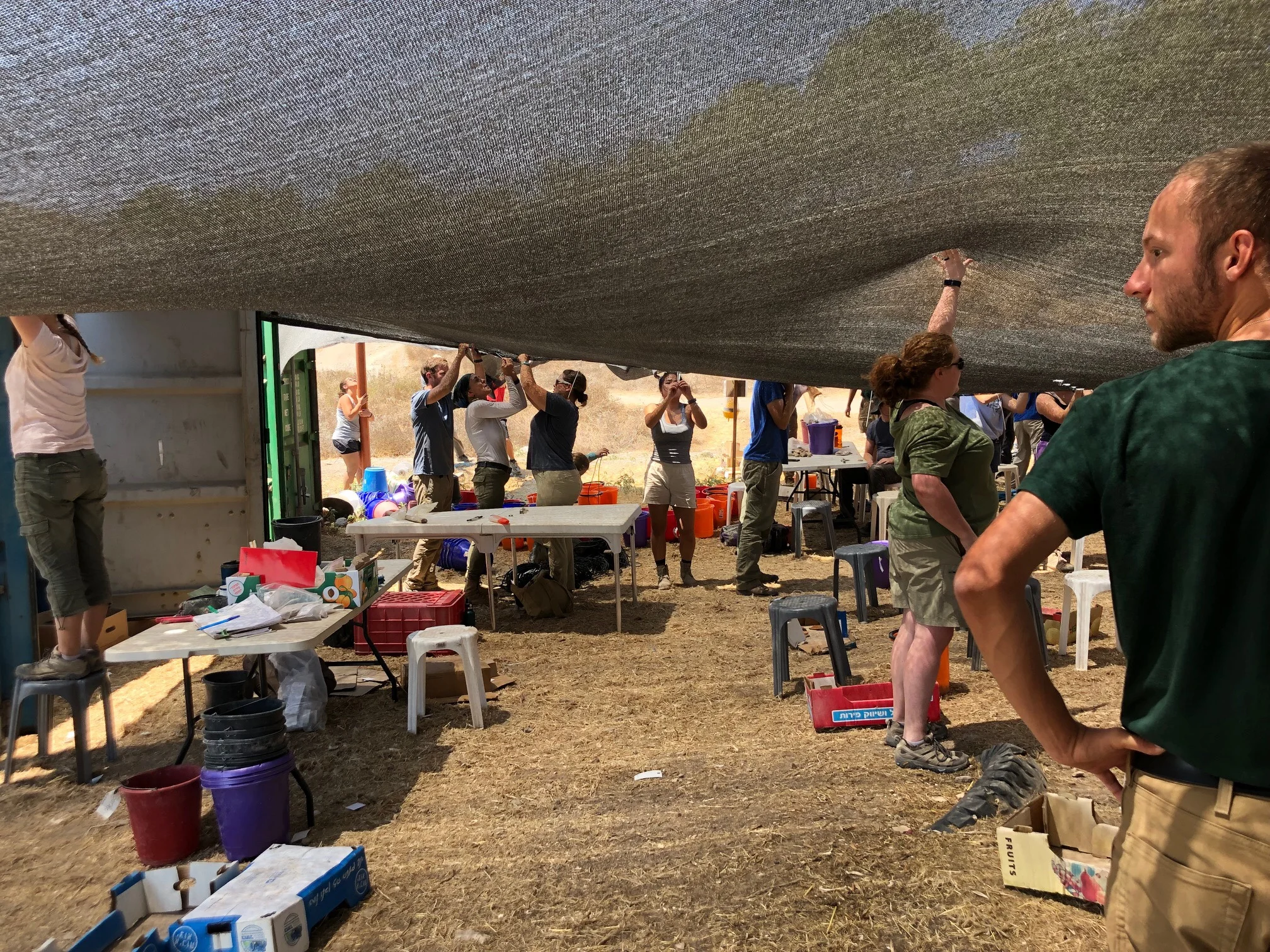 Staff and volunteers work to repair the pottery compound shade cloth after it was ripped off by a gust of wind