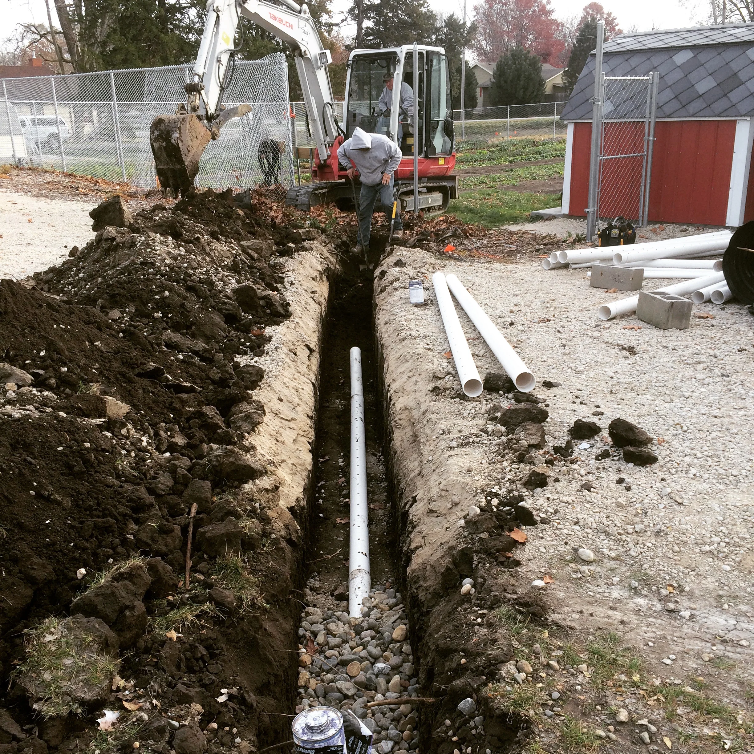 The crew dug a trench, laid the perforated pipe, topped it with rock, covered with fabric, and filled in the hole.