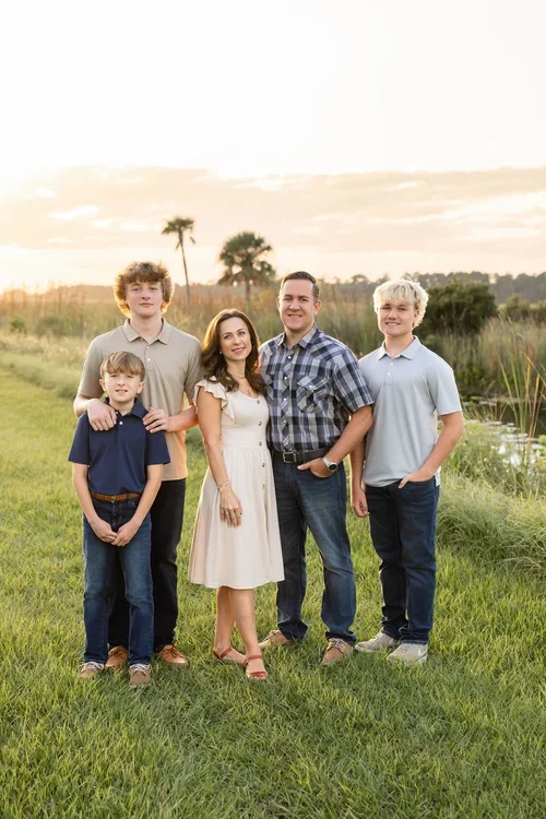 Outdoor family portrait in a natural field setting at sunset photographed by Dreamscape Photography + Video in Central Florida.