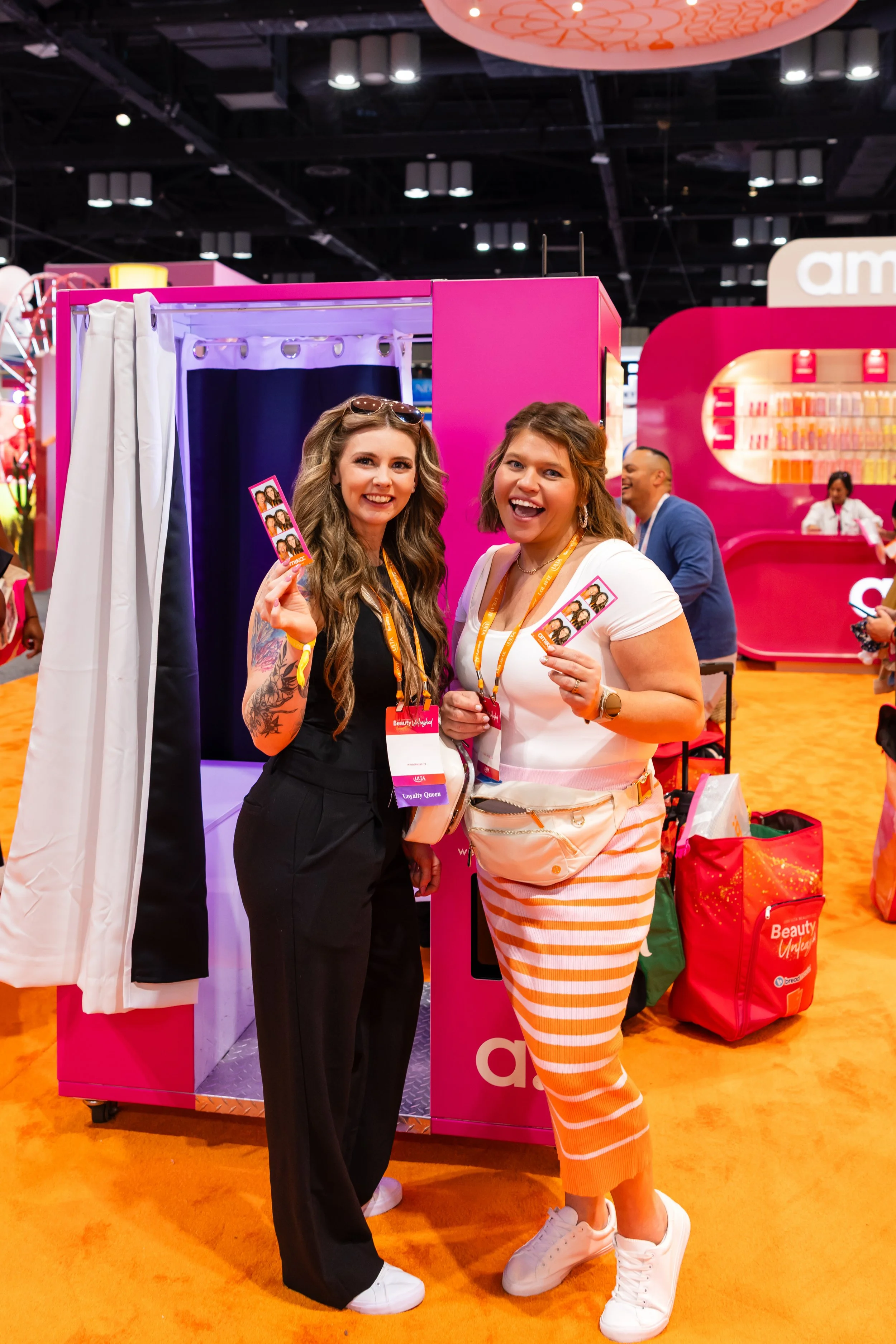 Guests smiling with photo booth strips during a brand activation event photographed by Dreamscape Photography + Video.