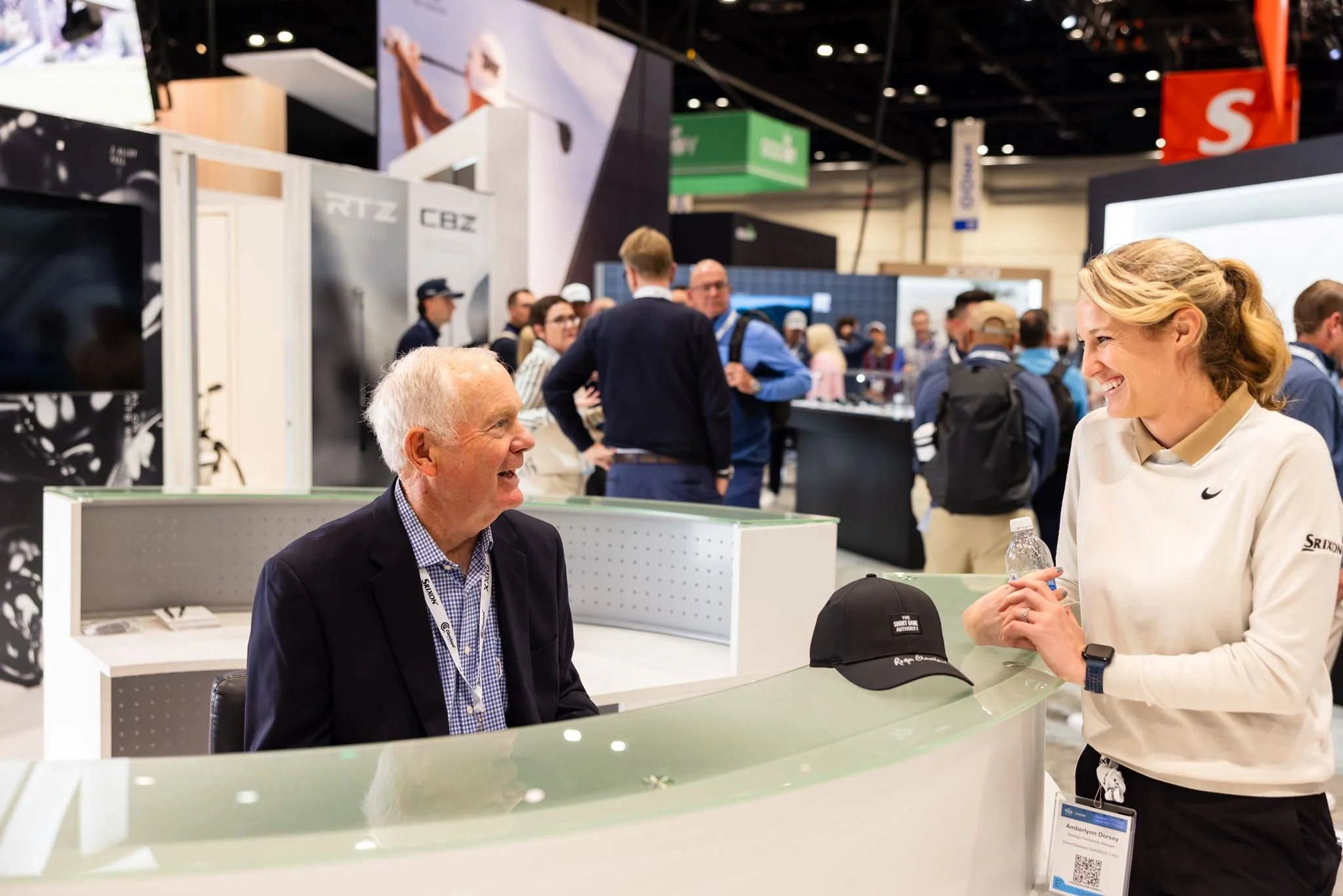 Candid trade show conversation with attendees smiling at a vendor booth photographed by Dreamscape Photography + Video in Orlando, Florida.