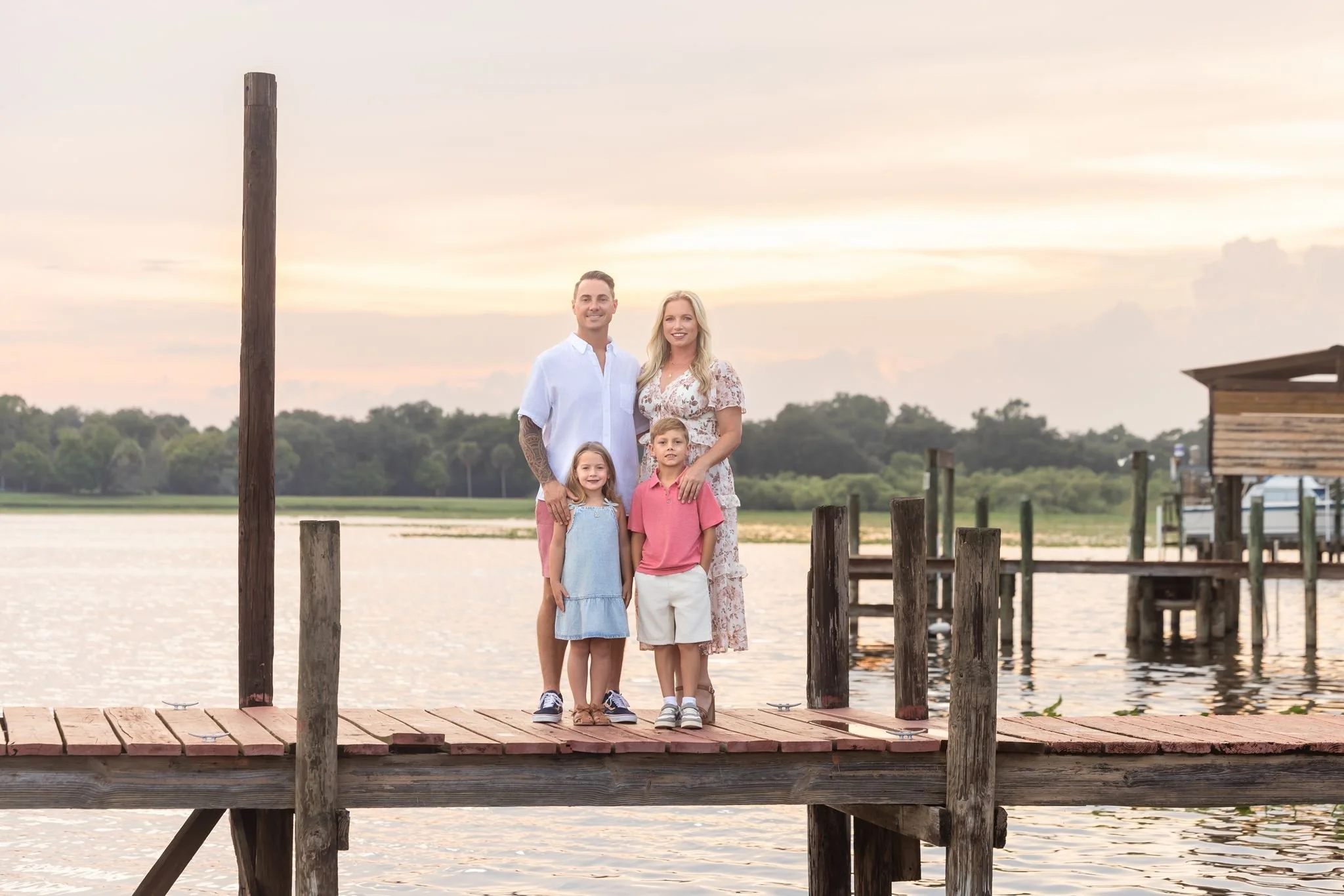 Outdoor family portrait on a dock at sunset photographed by Dreamscape Photography + Video in Central Florida.