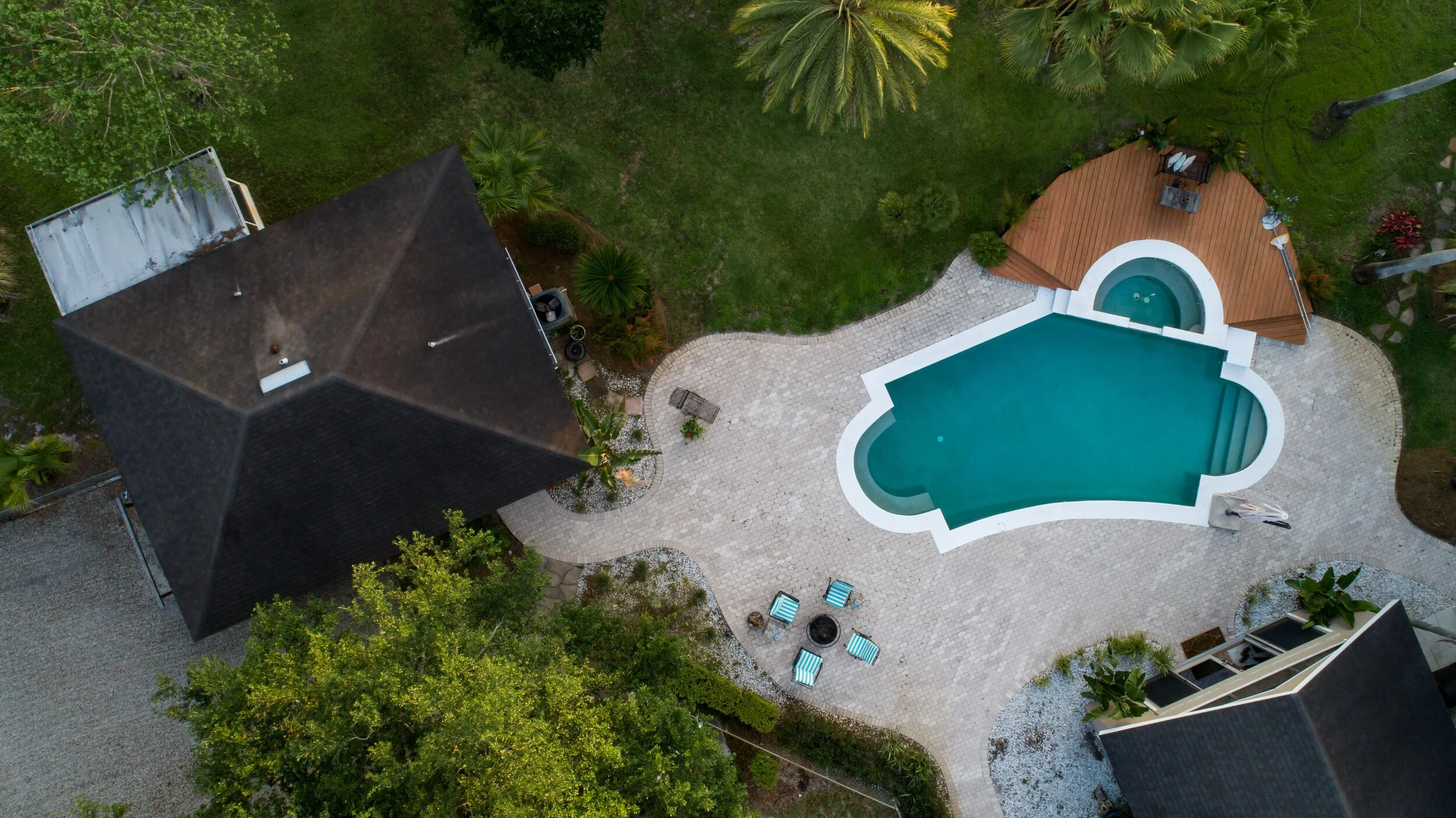Aerial real estate view showing a pool, patio, landscaping, and surrounding property layout.
