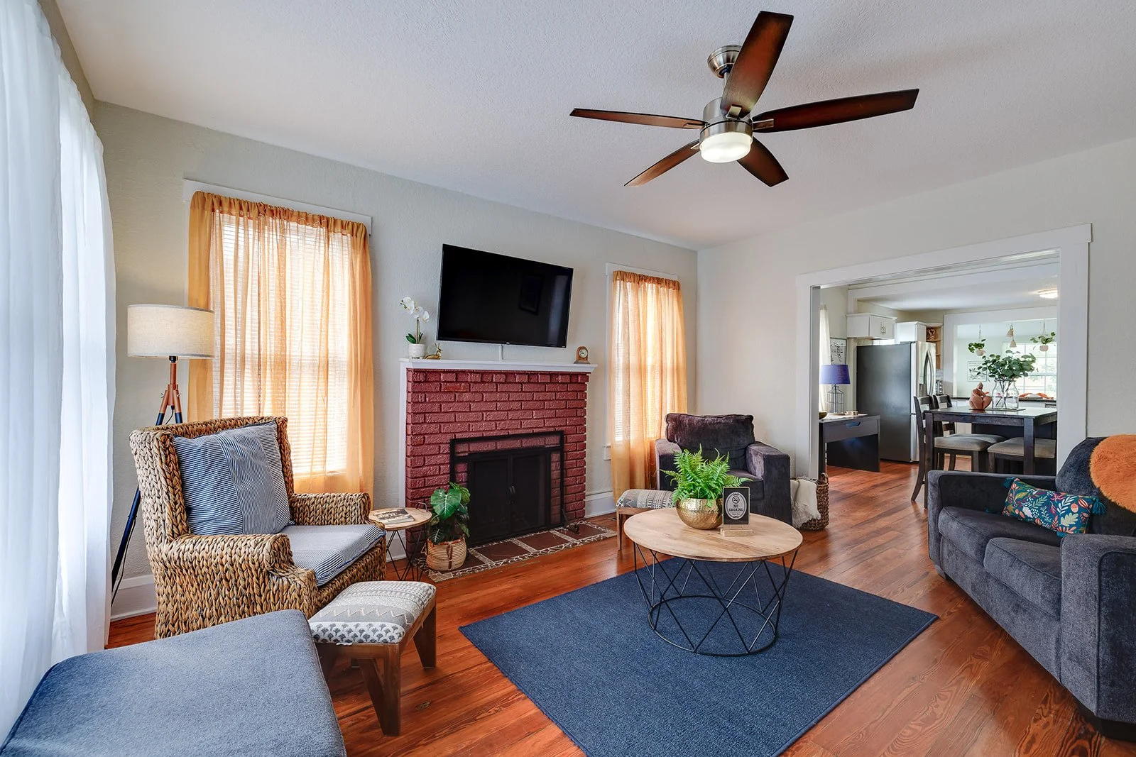 Cozy furnished living room with wood floors, fireplace, and a warm connected dining space.