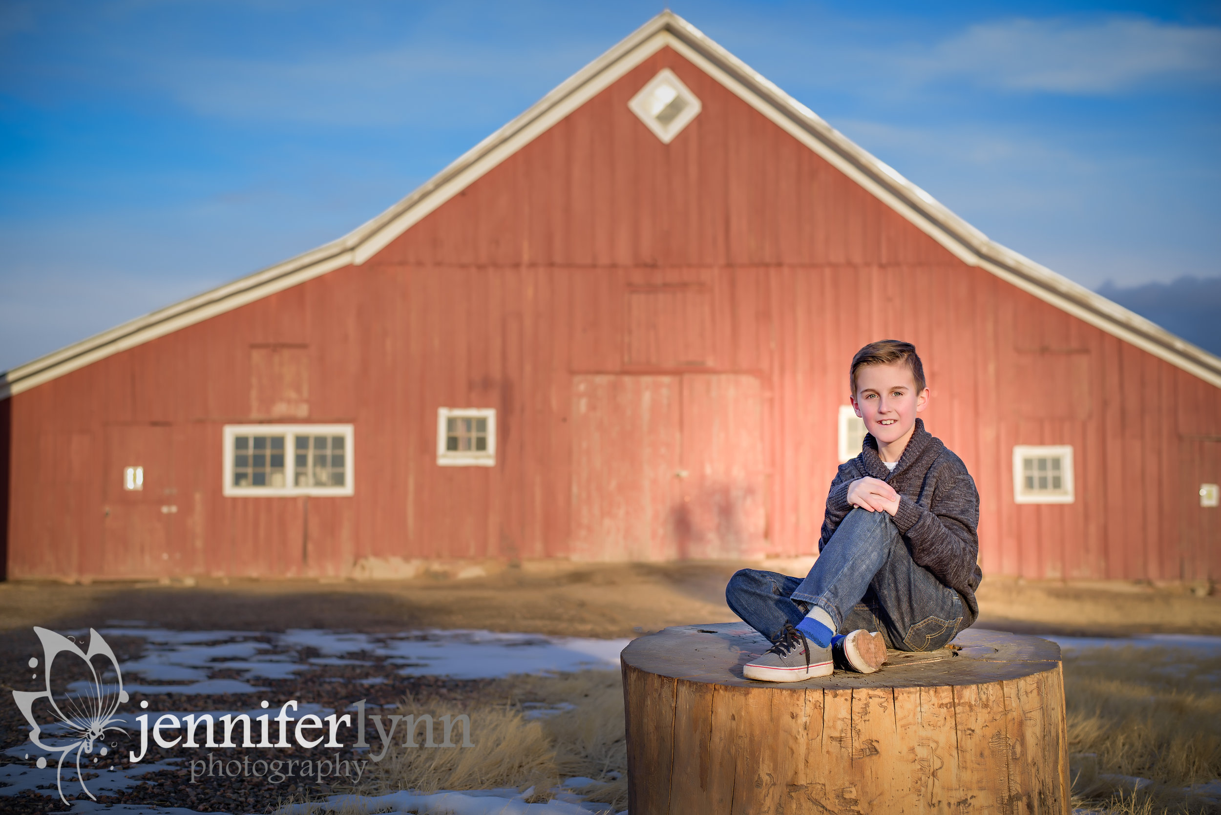 Son Sitting on Stump By Red Barn