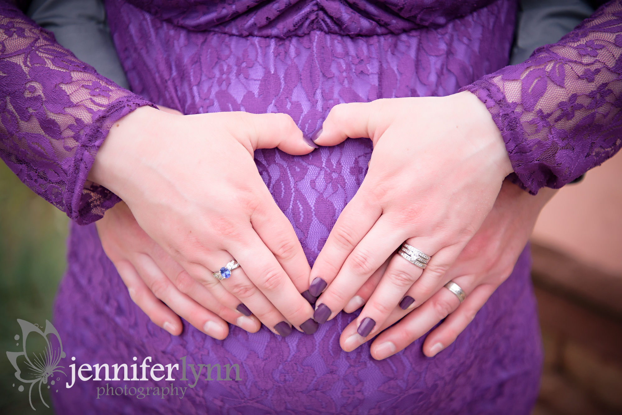 Two hands make a heart on a baby bump