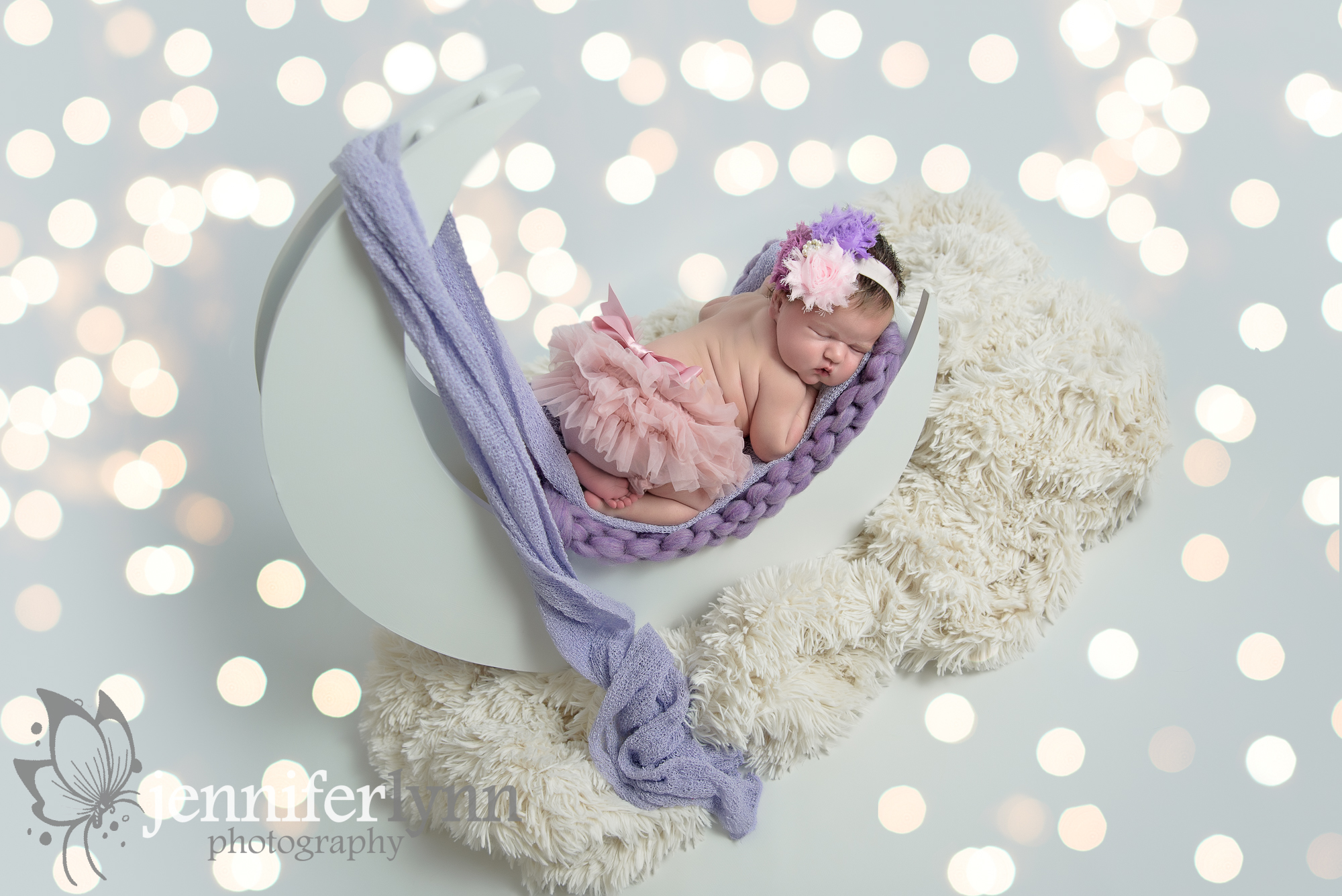 Newborn girl on moon prop with lights