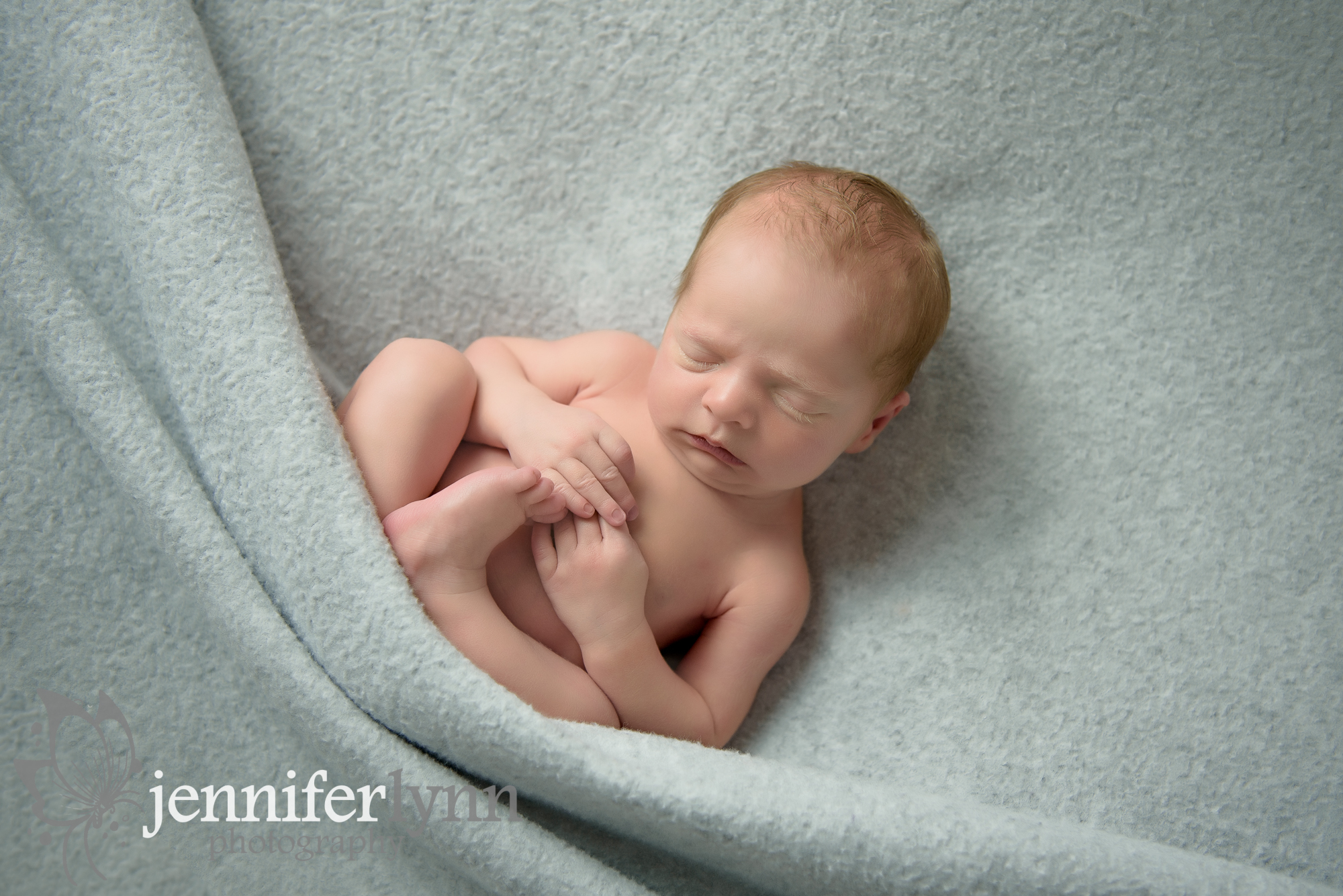 Newborn Boy on Back Feet Tucked Up Grey Blanket