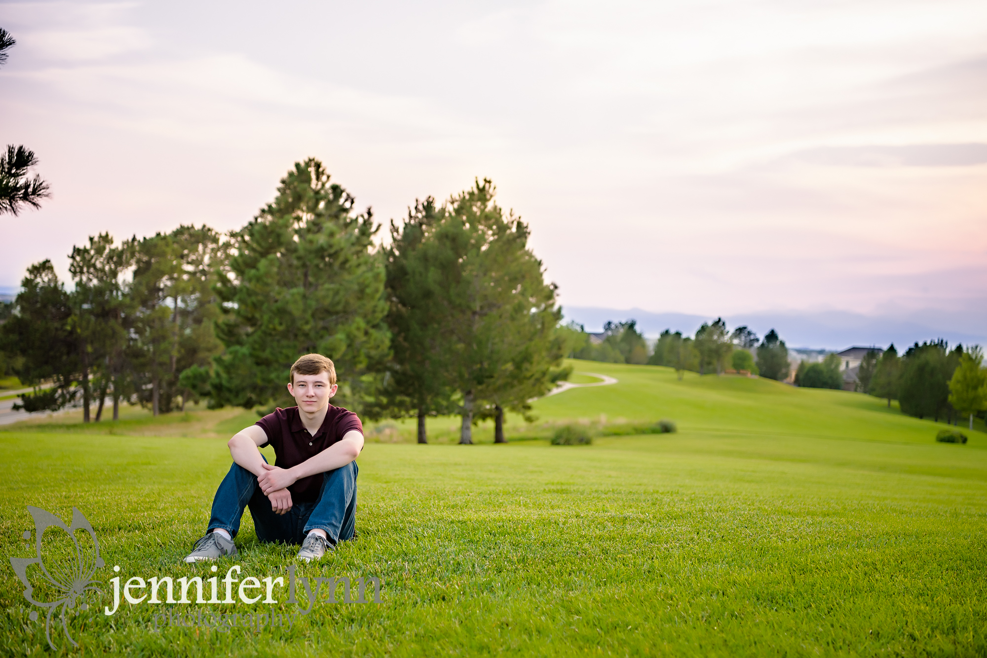 Senior Boy Sitting on Green Hill Mountains Sunset
