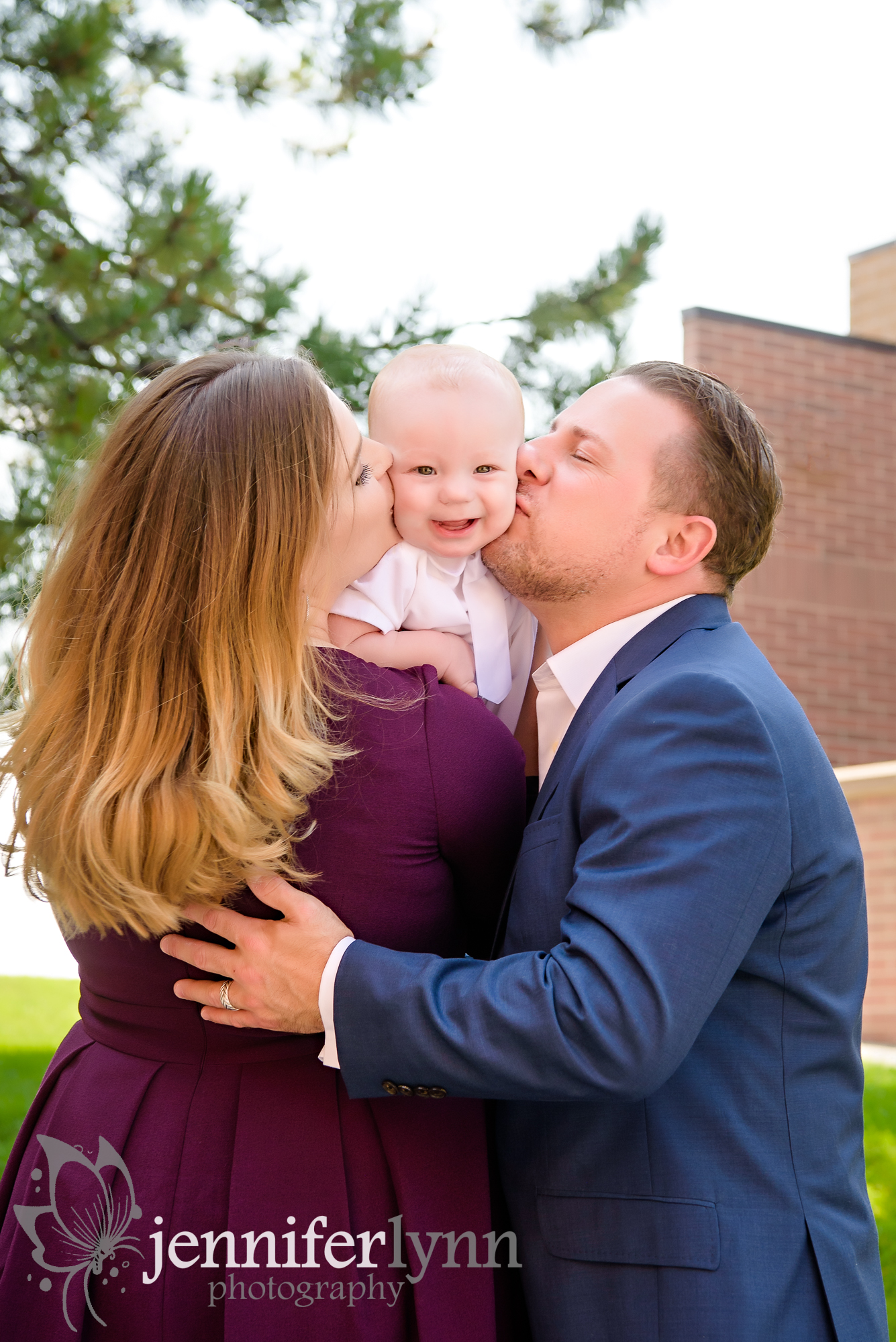 Family of Three kissing baby