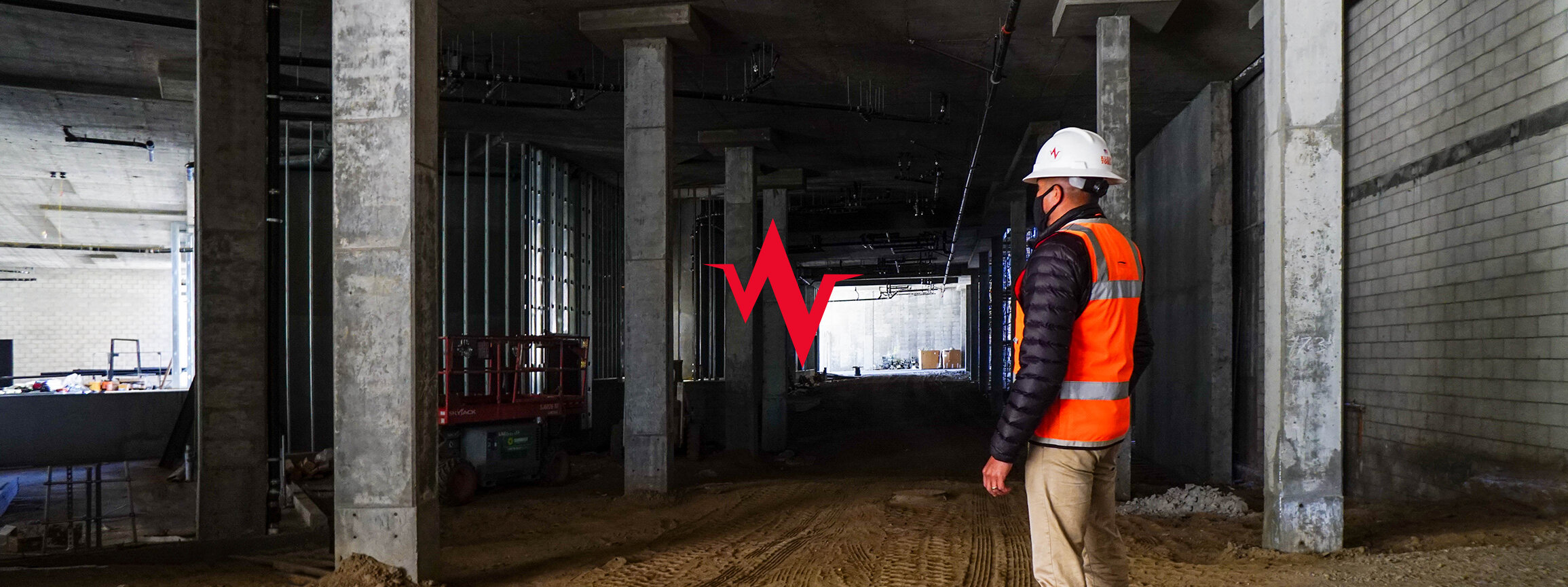 Worker in a white helmet and orange vest standing in underground structure