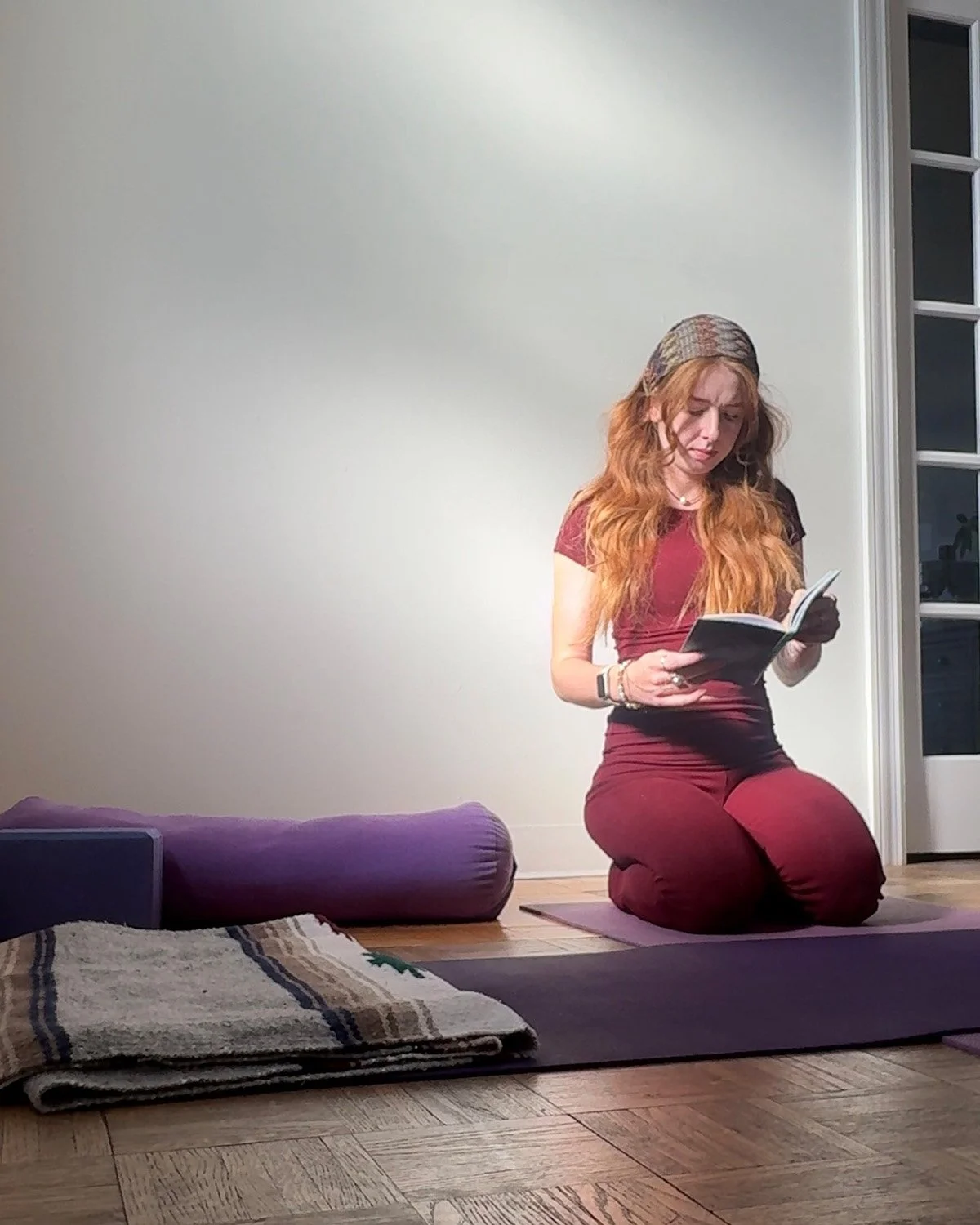 Yoga teacher Kylie Grogan sitting on a mat reading during a quiet moment at Yoga Among Friends in Downers Grove.