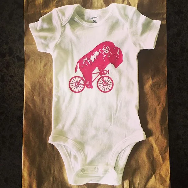 Babies everywhere told us they wanted in on that bike it, Buffalo onesie game. So we said, &quot;Hey baby, here you go!&quot; @bikeitbuffalo #bikeitbuffalo #ridewithoride #baby #onesie #babyfashion #bikes #heybaby