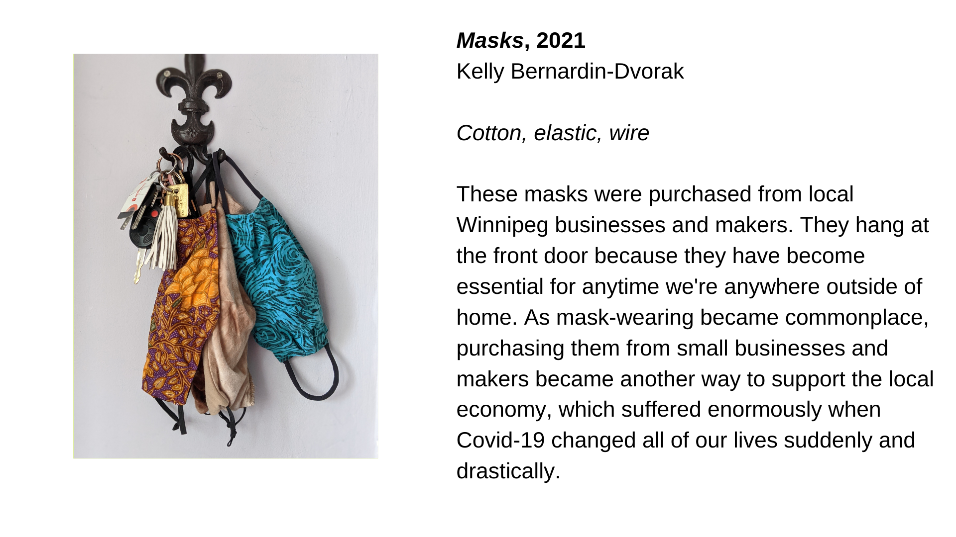  Colourful cloth masks hanging from a coat hook with keys. Next to this image, the text “Masks, 2021 - Kelly Bernardin-Dvorak. Cotton, elastic, wire. These masks were purchased from local Winnipeg businesses and makers.  They hang at the front door b