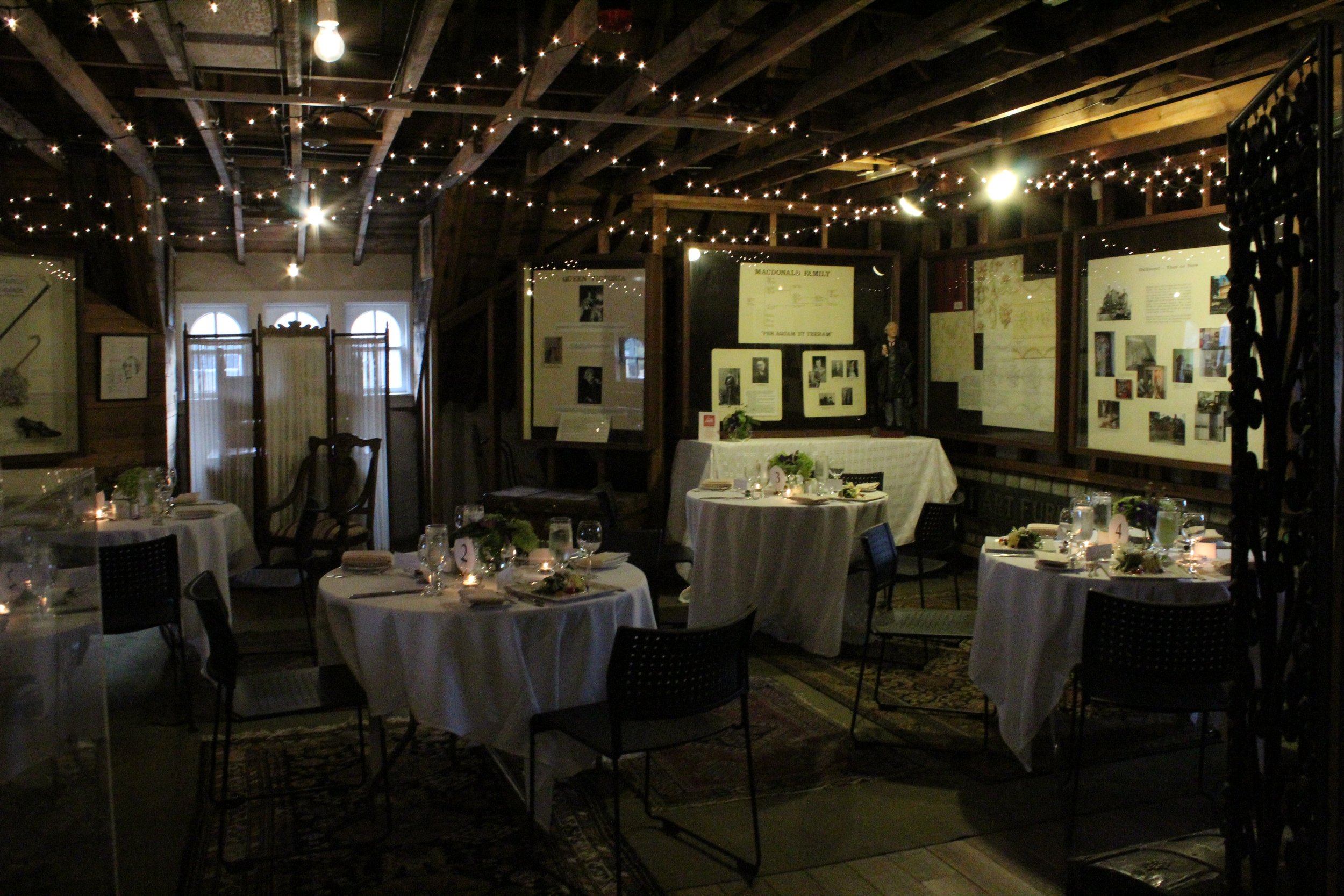  Dalnavert’s attic with several small tables set for a fancy dinner with white table cloths and place settings 