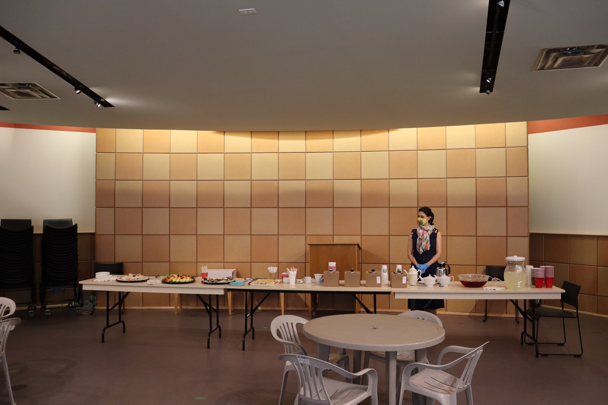  A woman standing behind several long tables with food on them in the visitors’ centre 