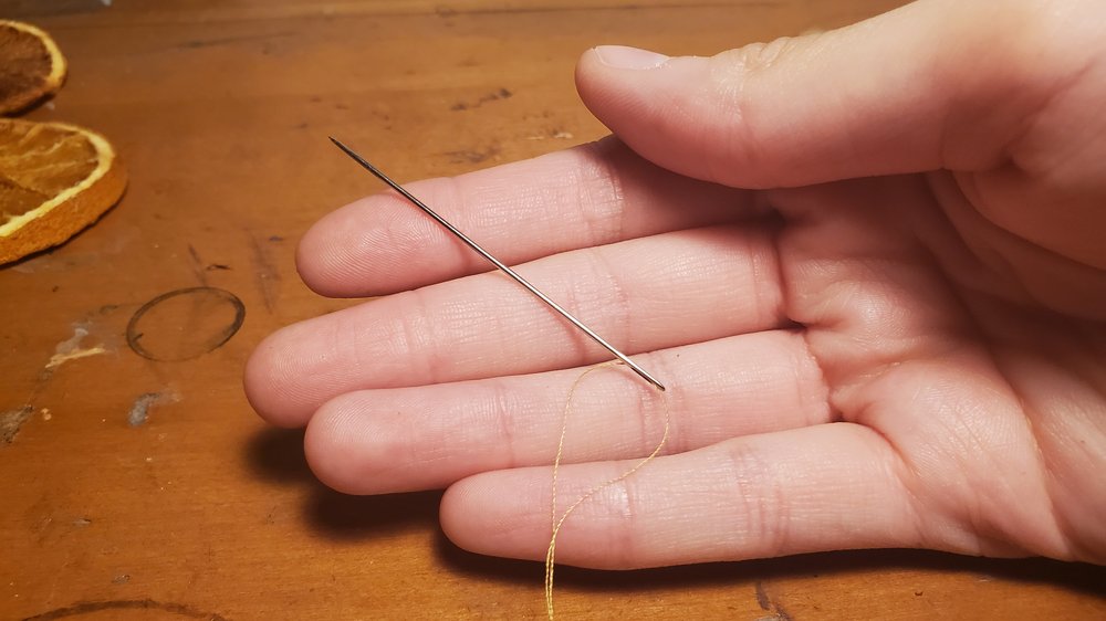  Cut a string of thread at the length that you want your garland to be and thread it through the needle.&nbsp; 