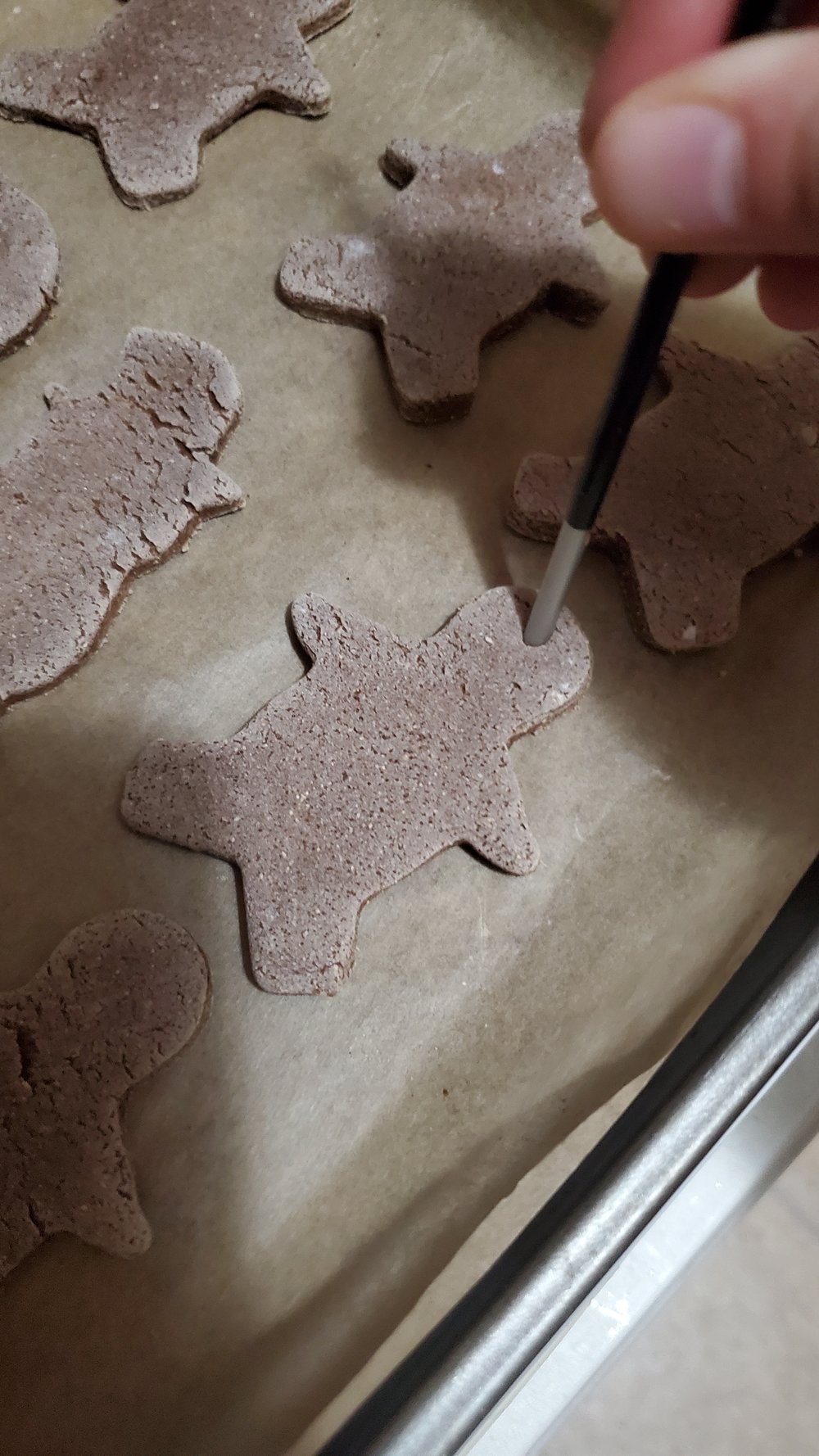  Using the end of a paint brush or another sharp tool, pierce holes into the tops of the cookies (or wherever you wish to hang them from.)   (note: I only remembered this step when my cookies were already in the oven, which is why they are already on