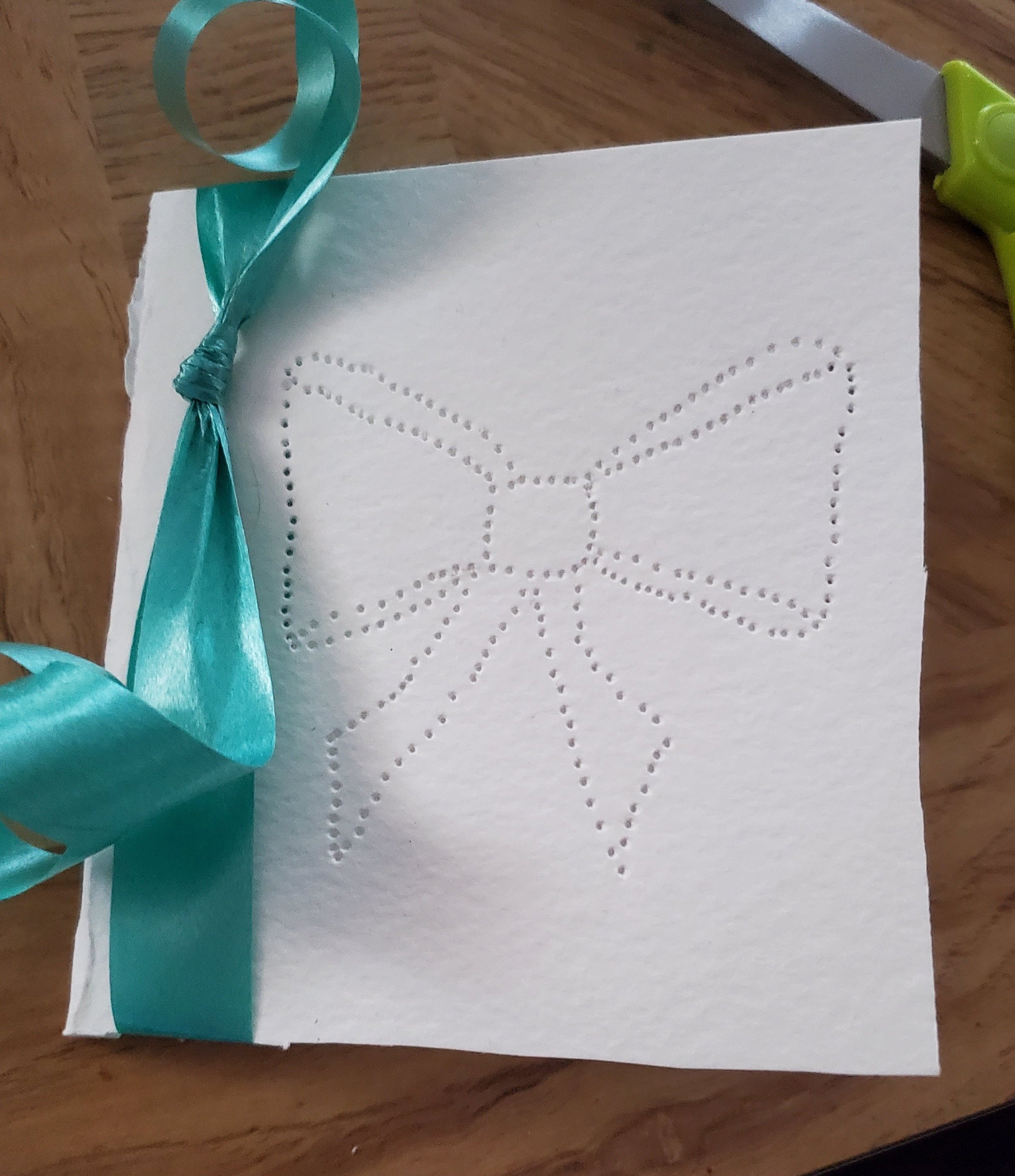  Take the ribbon and tie it around the face of the card, close to the fold. 