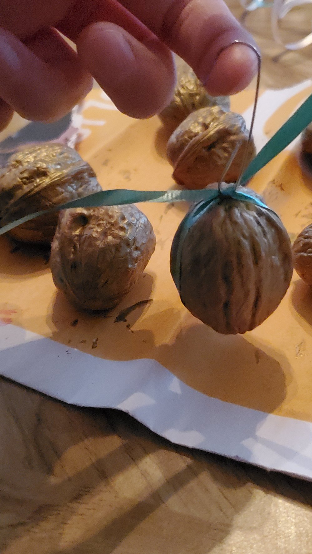  Once the paint has fully dried, tie a ribbon around the walnut and slip an ornament hook through it.  