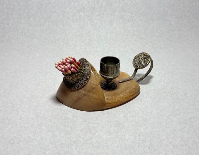 a light brown carved cattle hoof, with intracate brass fixtures.