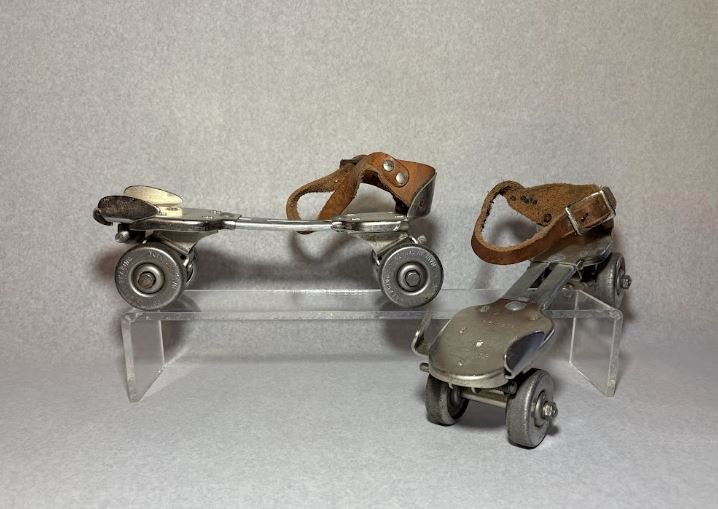 a pair of four-wheel silver metail roller skates, with leather straps.