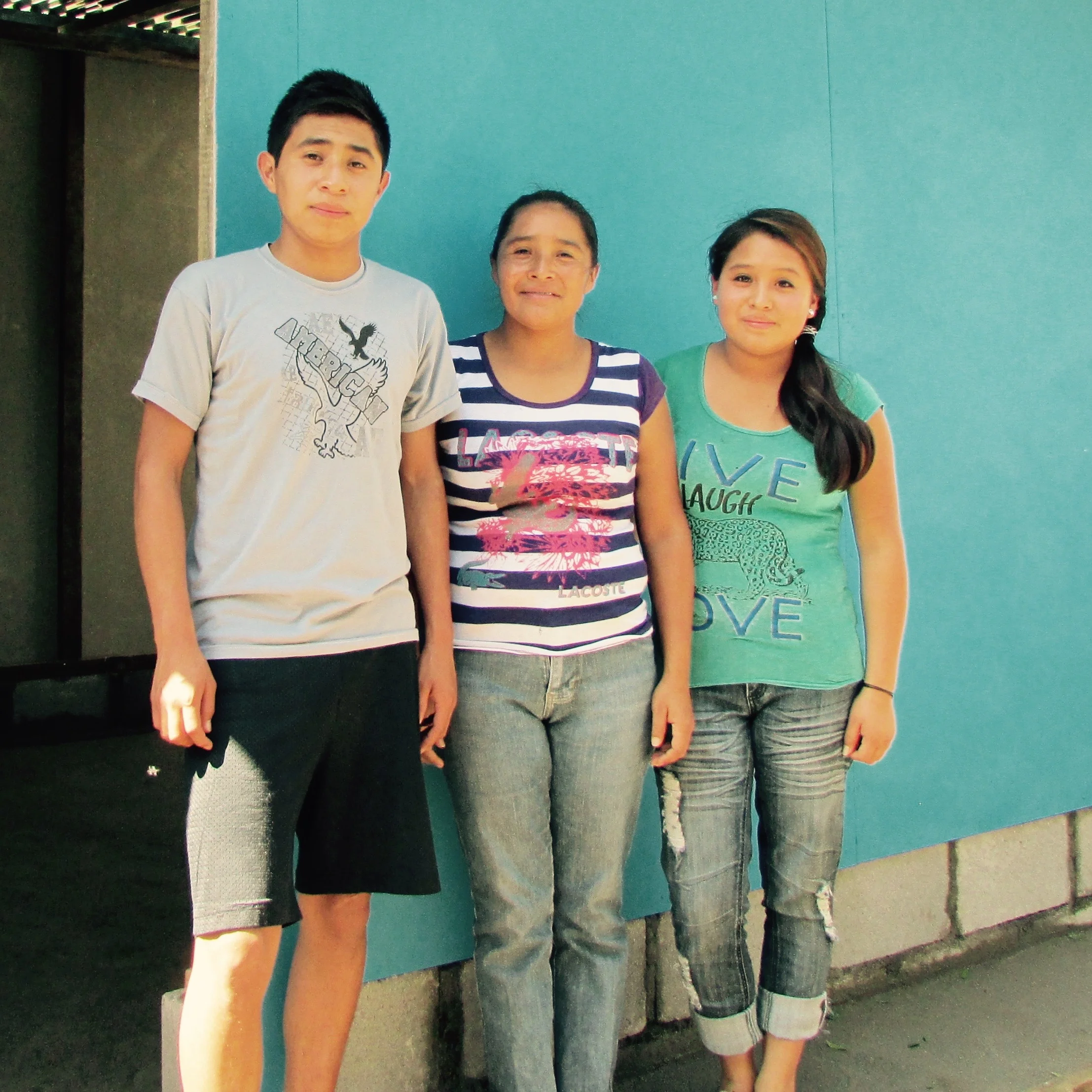 Maria (center) with two of her children. Pictured in front of their new home
