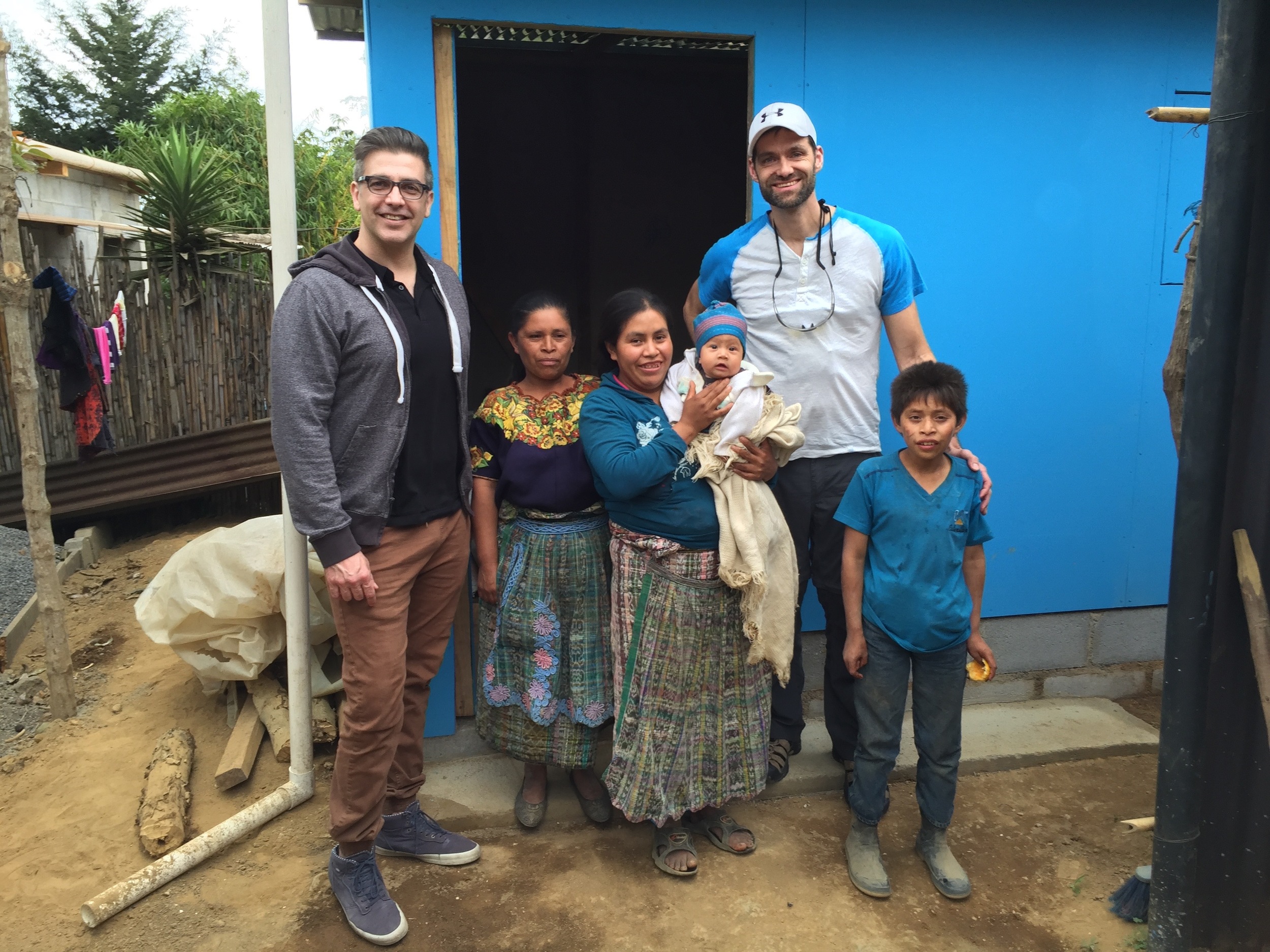 Rob and Sean with Madelin and some of her family in front of new home