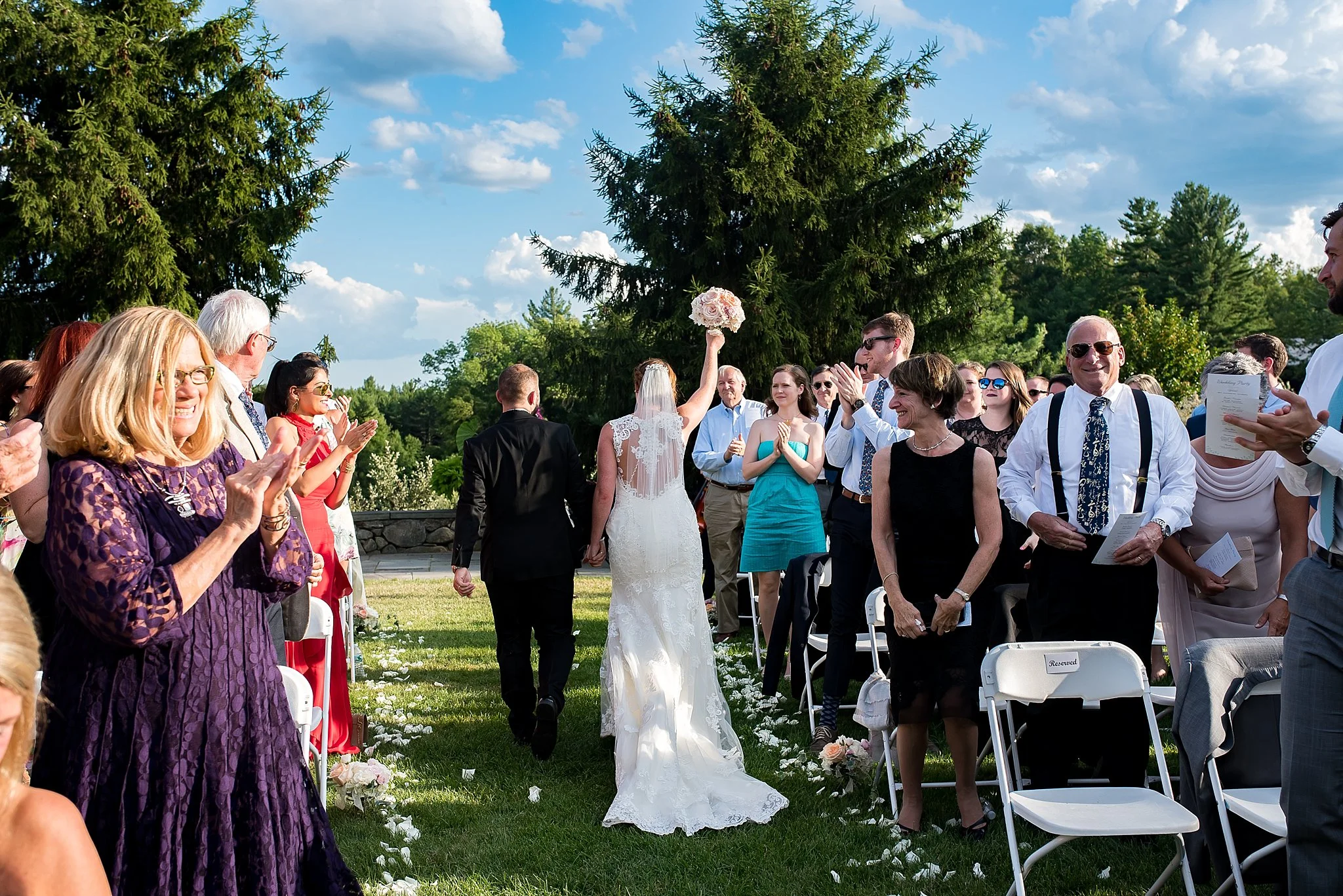 small wedding crowd cheers as bride and groom walk down the aisle
