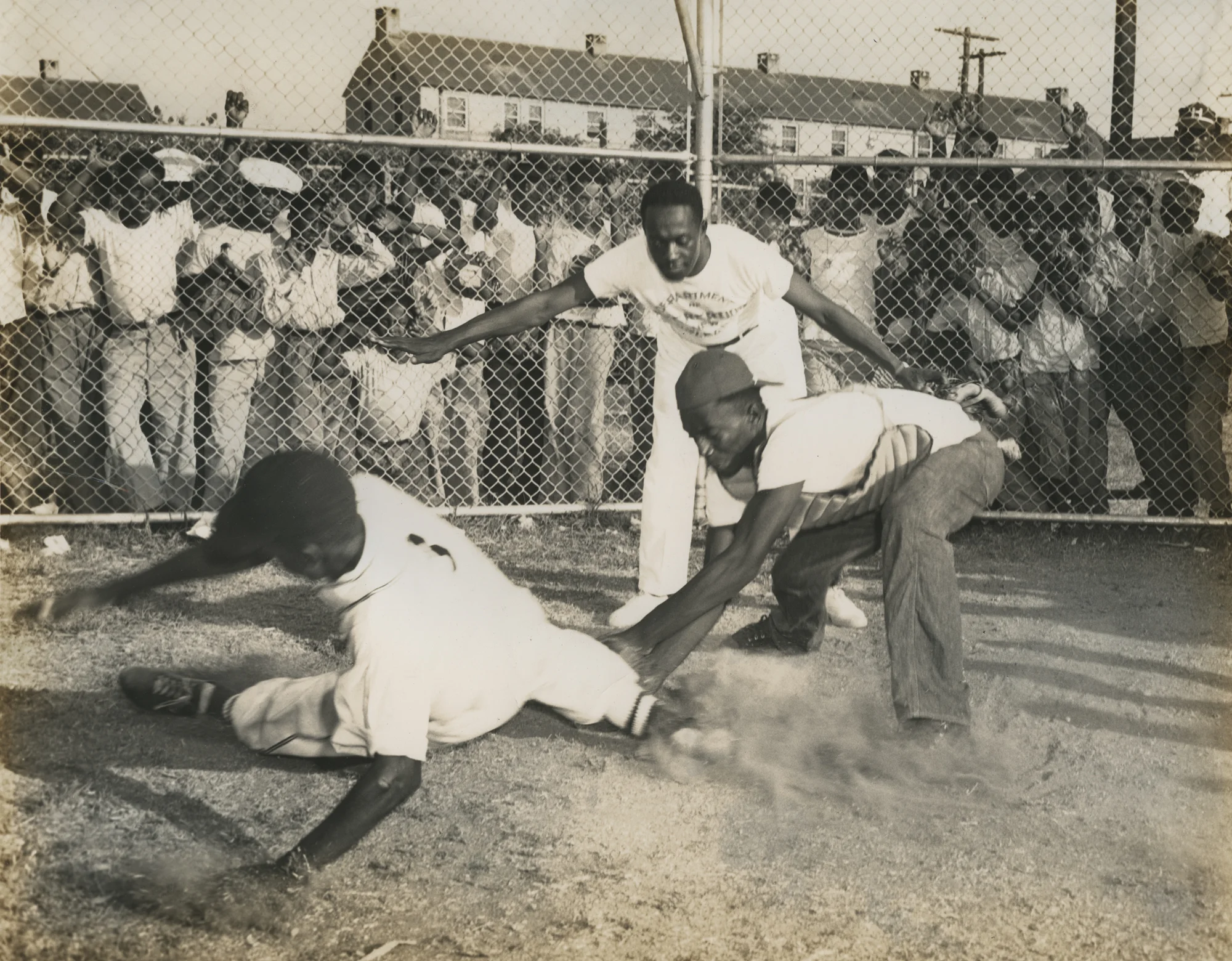 Baseball player sliding into home plate with umpire signalling "safe." New Orleans (La.) Recreation Dept. Scrapbook photographs, 1947-1948