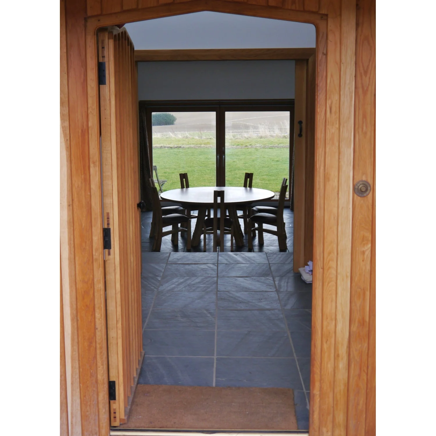 View through front door of Split-leg Dining Table and Chairs in Oak and Leather by Alasdair Wallace