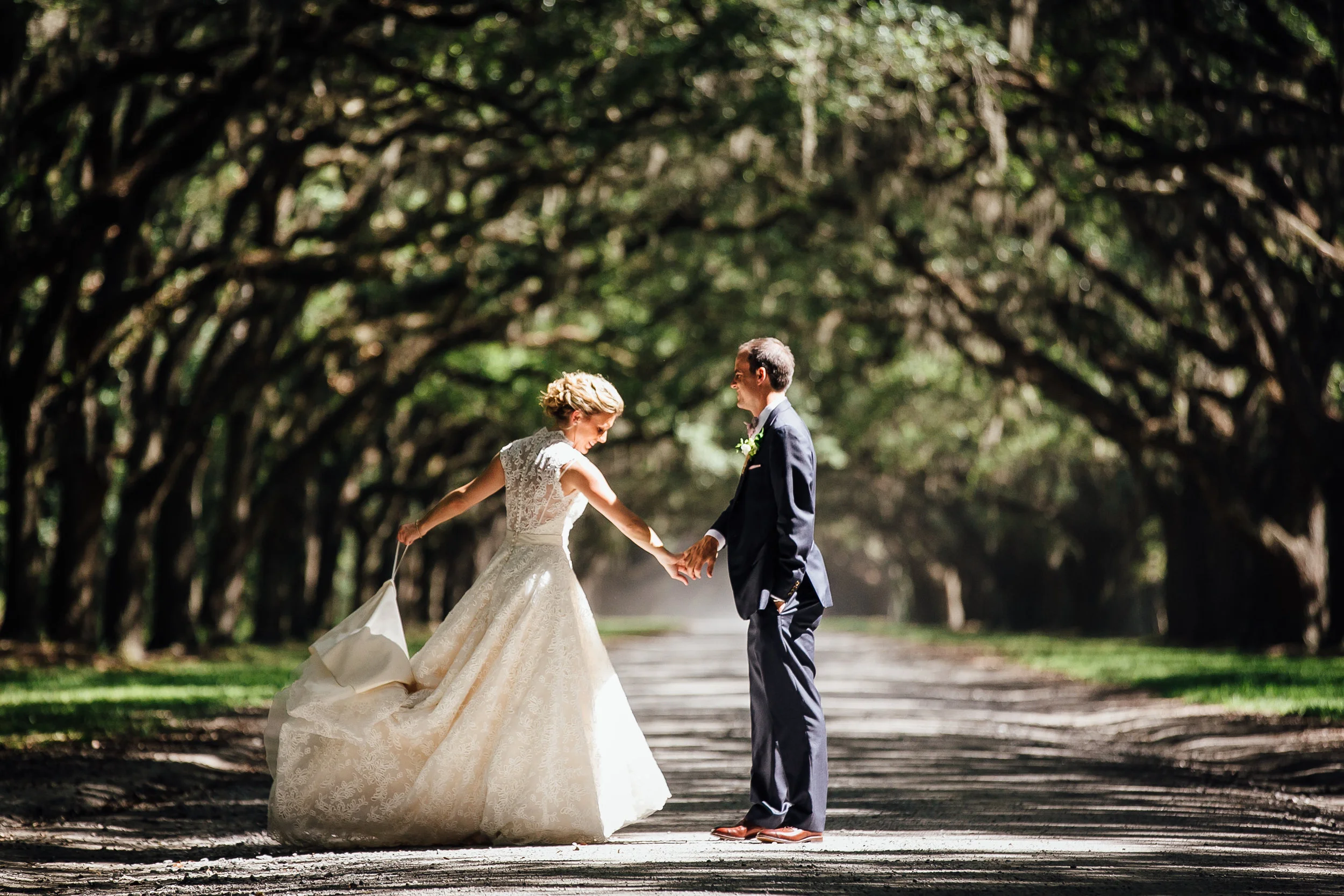 Couple Hold Hands on Oak Lined Road - Middle Georgia Wedding Photographer