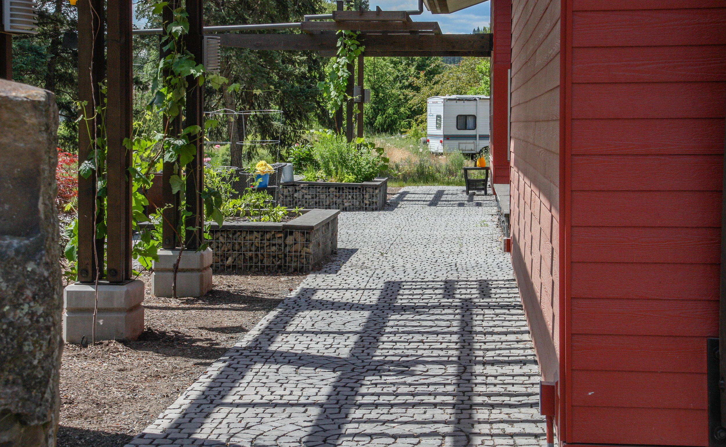 pergola over stamped concrete pathway with gabion raised beds
