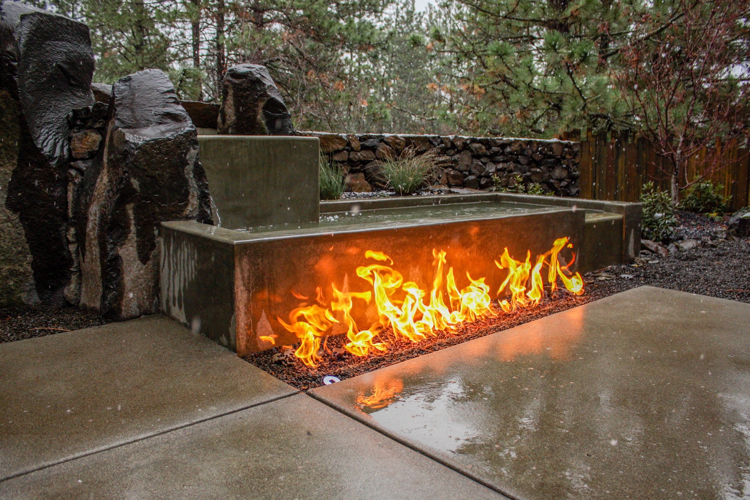concrete and basalt column water feature with in ground gas fire pit