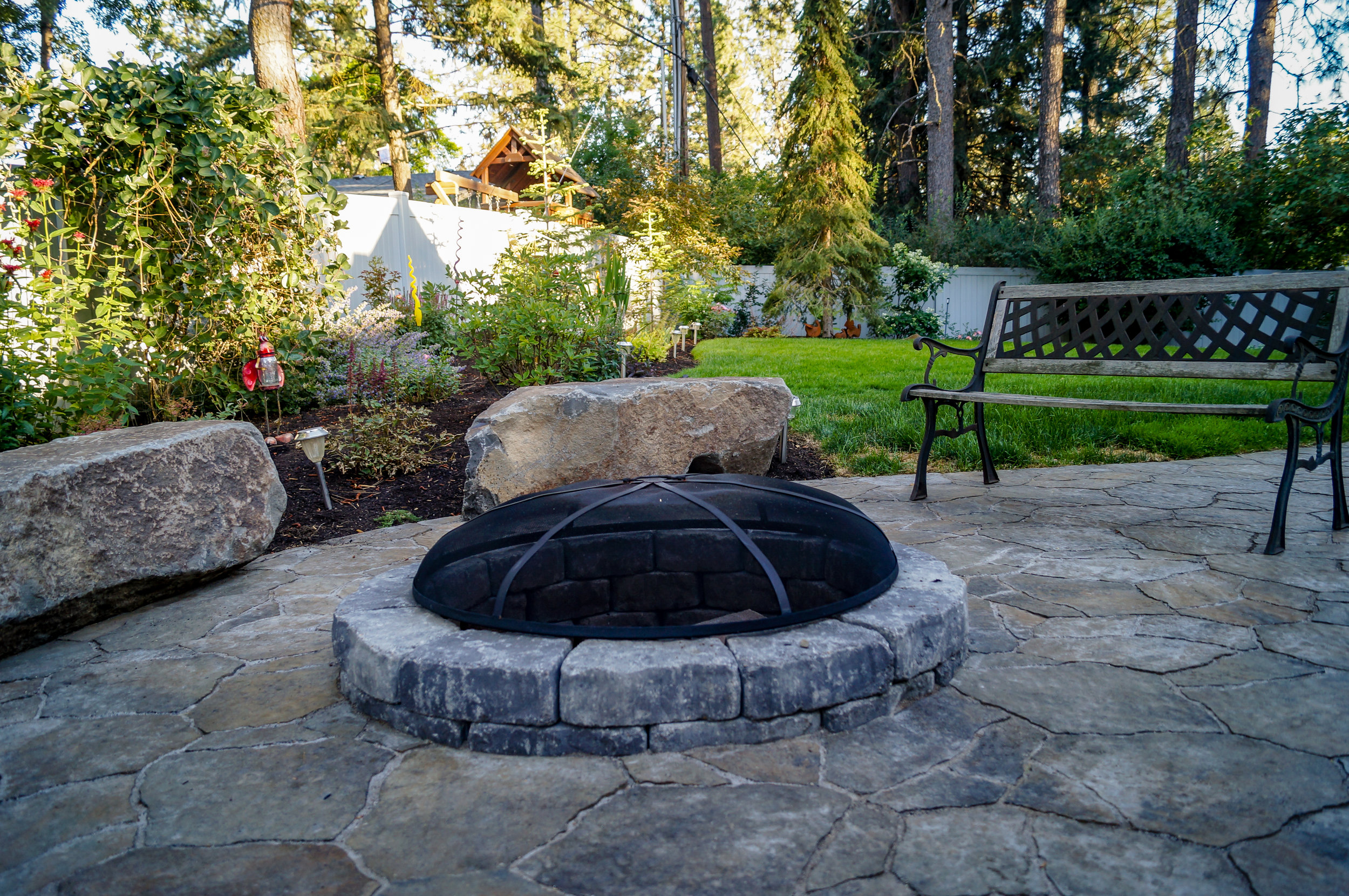 sunken fire pit and basalt bench rocks with belgard mega arbel patio in spokane landscape