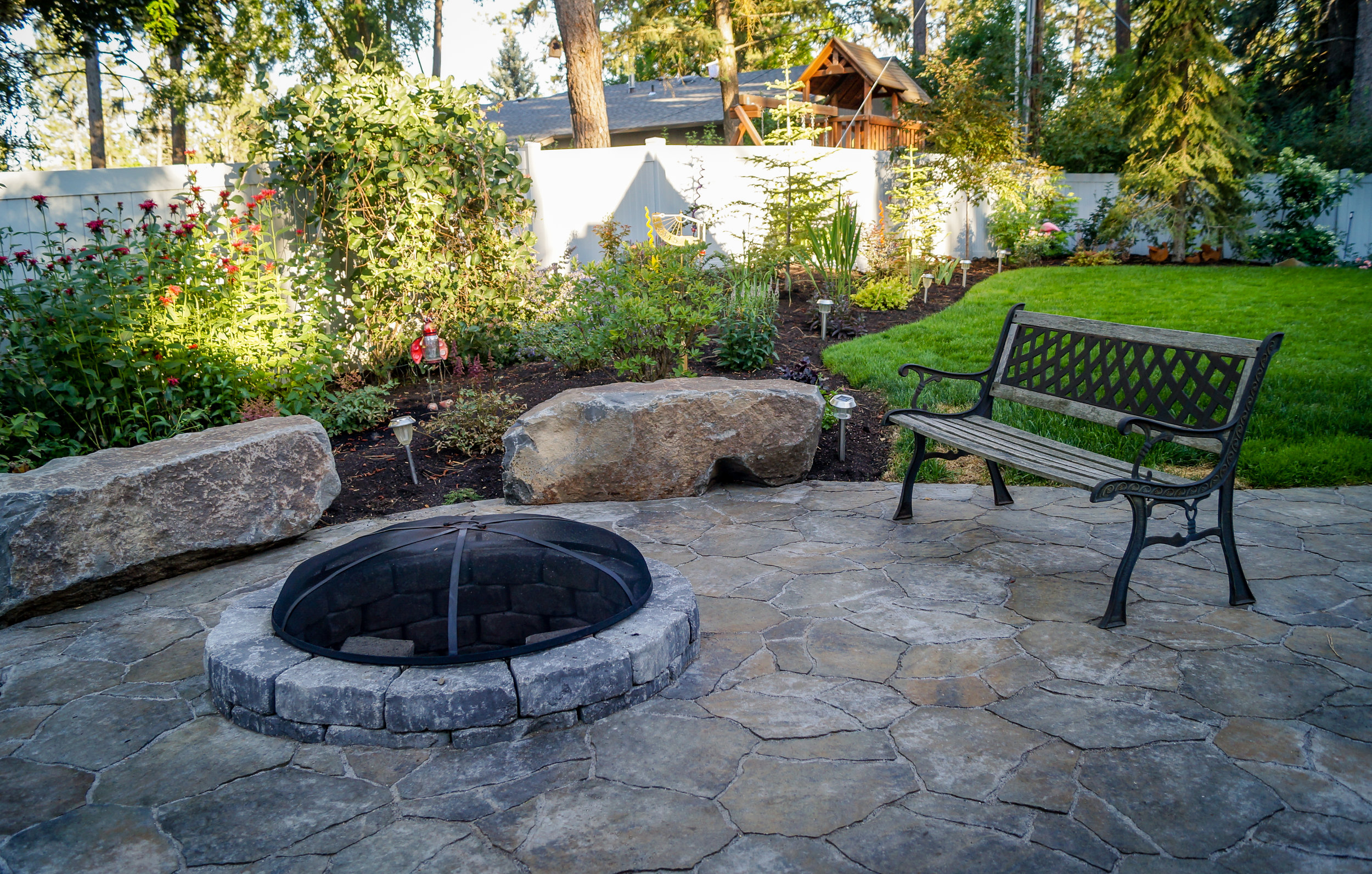 northwest landscaping with stone bench rocks and paver patio around fire pit